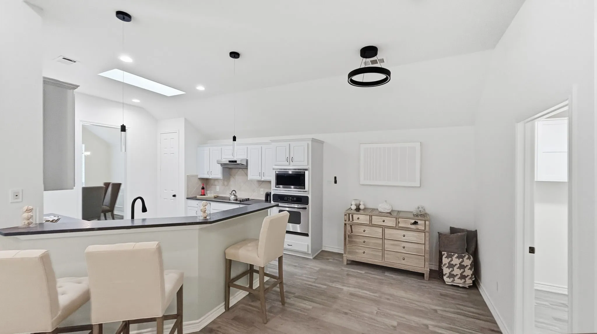 Vaulted ceilings, a skylight, wood-finish flooring, recessed lighting, and a breakfast bar