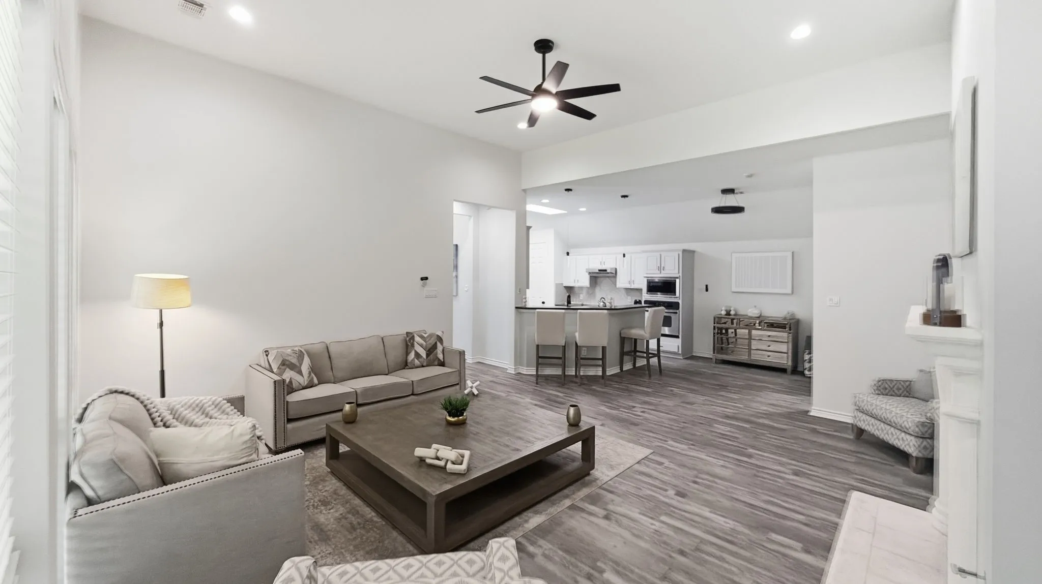Vaulted ceiling with recessed lighting, wood-finish flooring, built-in fireplace, and kitchen with breakfast bar