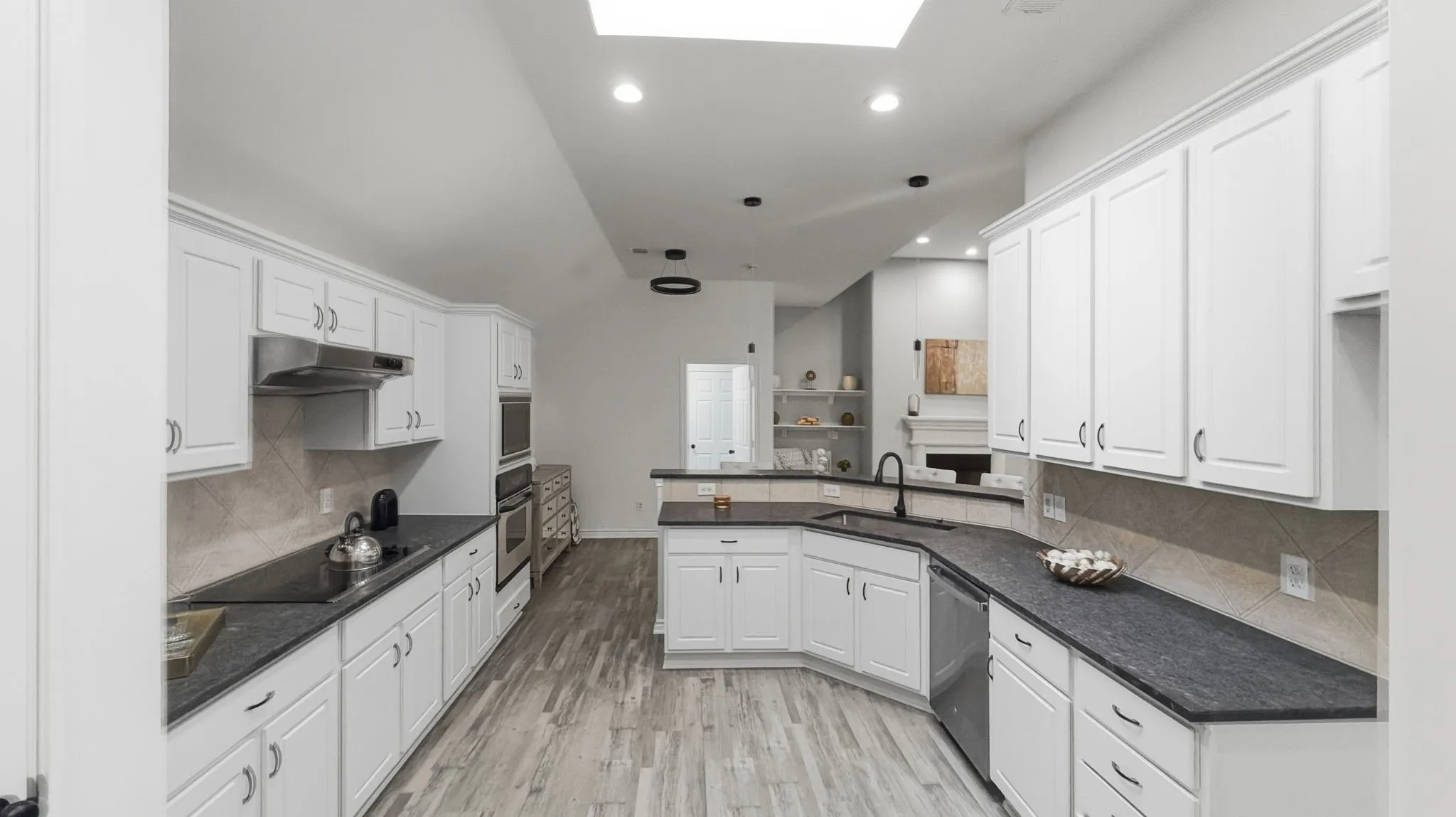 Modern kitchen featuring white cabinetry, dark countertops, a built-in oven, and wood-finish flooring