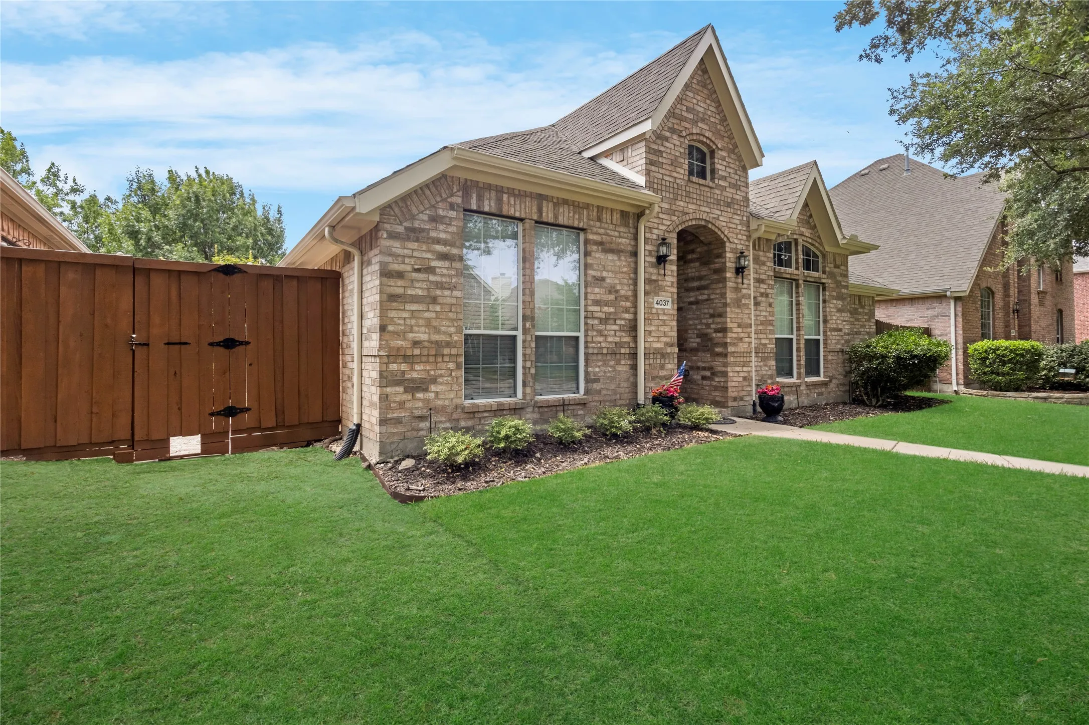 Brick exterior with gabled rooflines, arched entry, and  landscaping