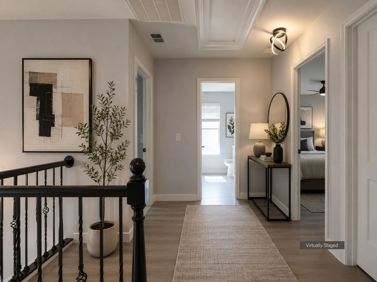 Upper-level hallway with wood-finish flooring, white trim, and a black wrought iron staircase railing