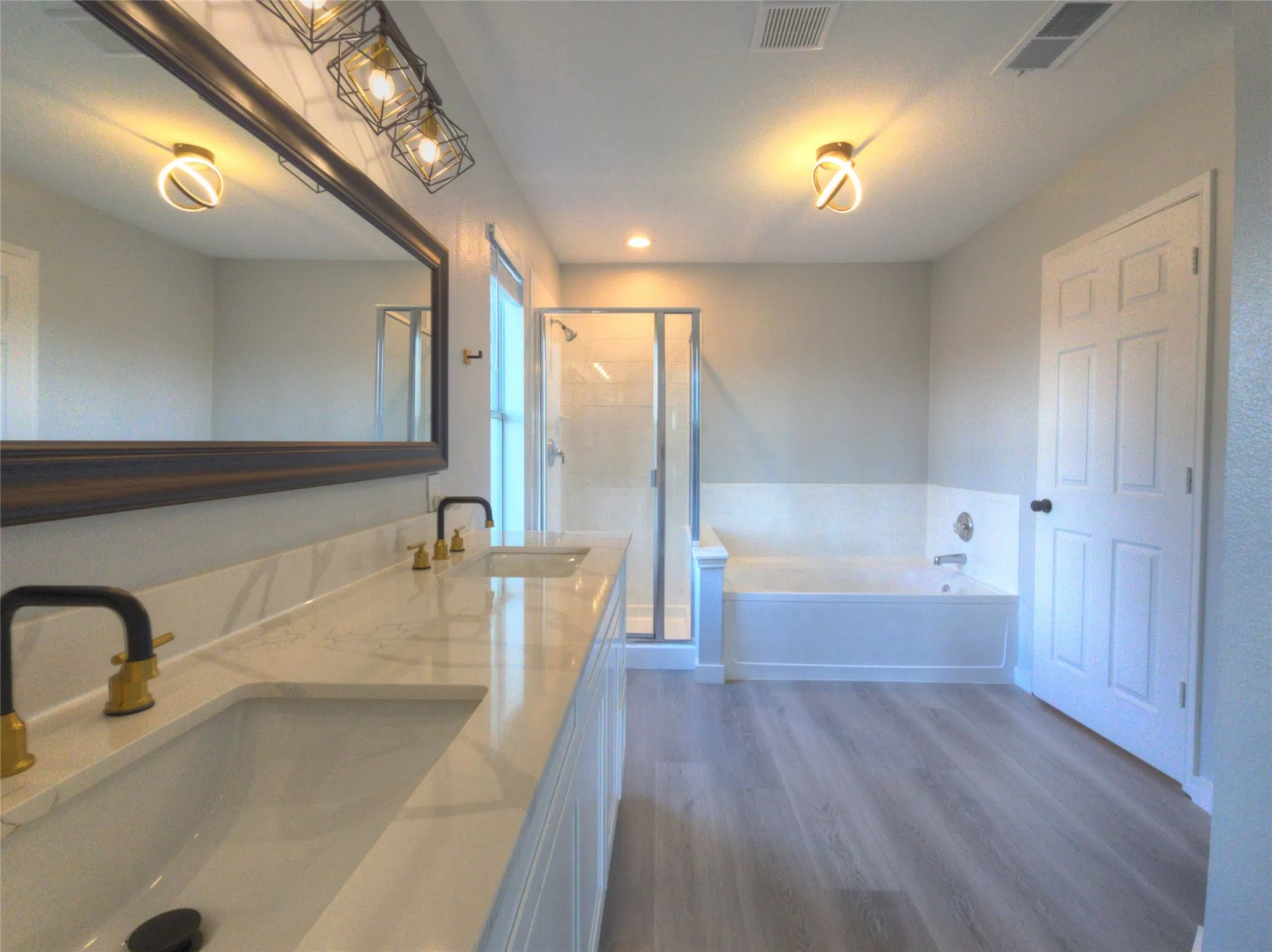 Dual vanity with stone-look countertop and under-mount sinks featuring black and gold-tone fixtures