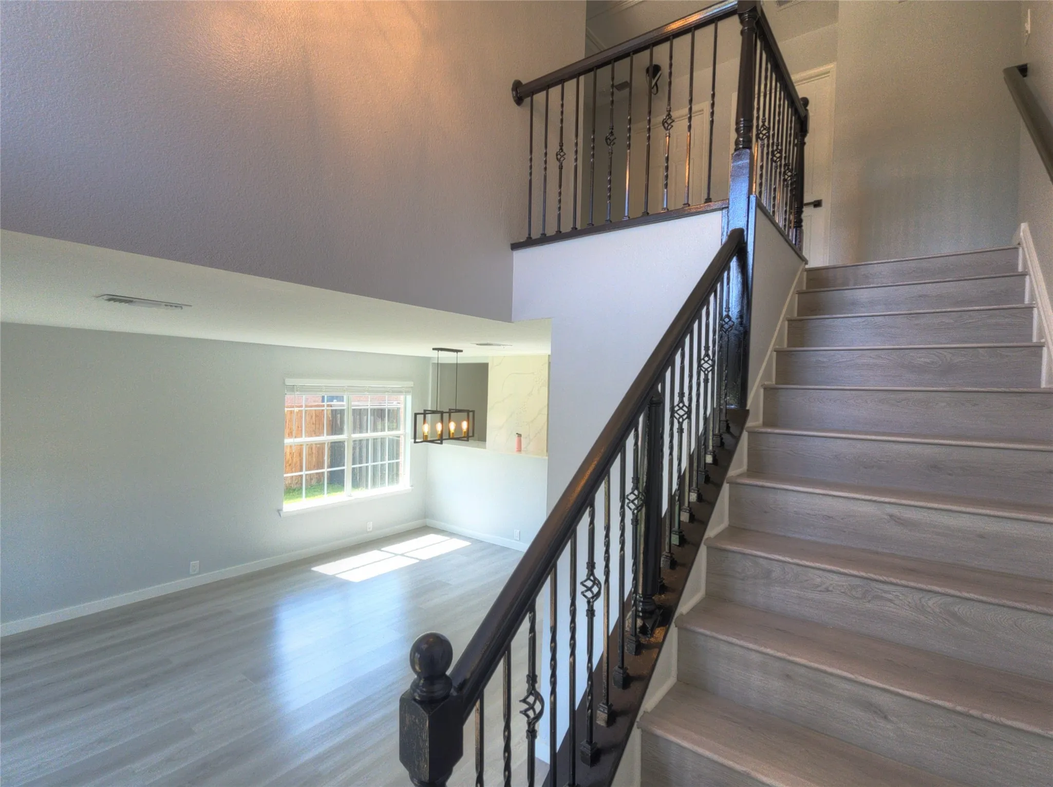 Spacious interior featuring a grand staircase with wrought iron balusters and dark wood handrails