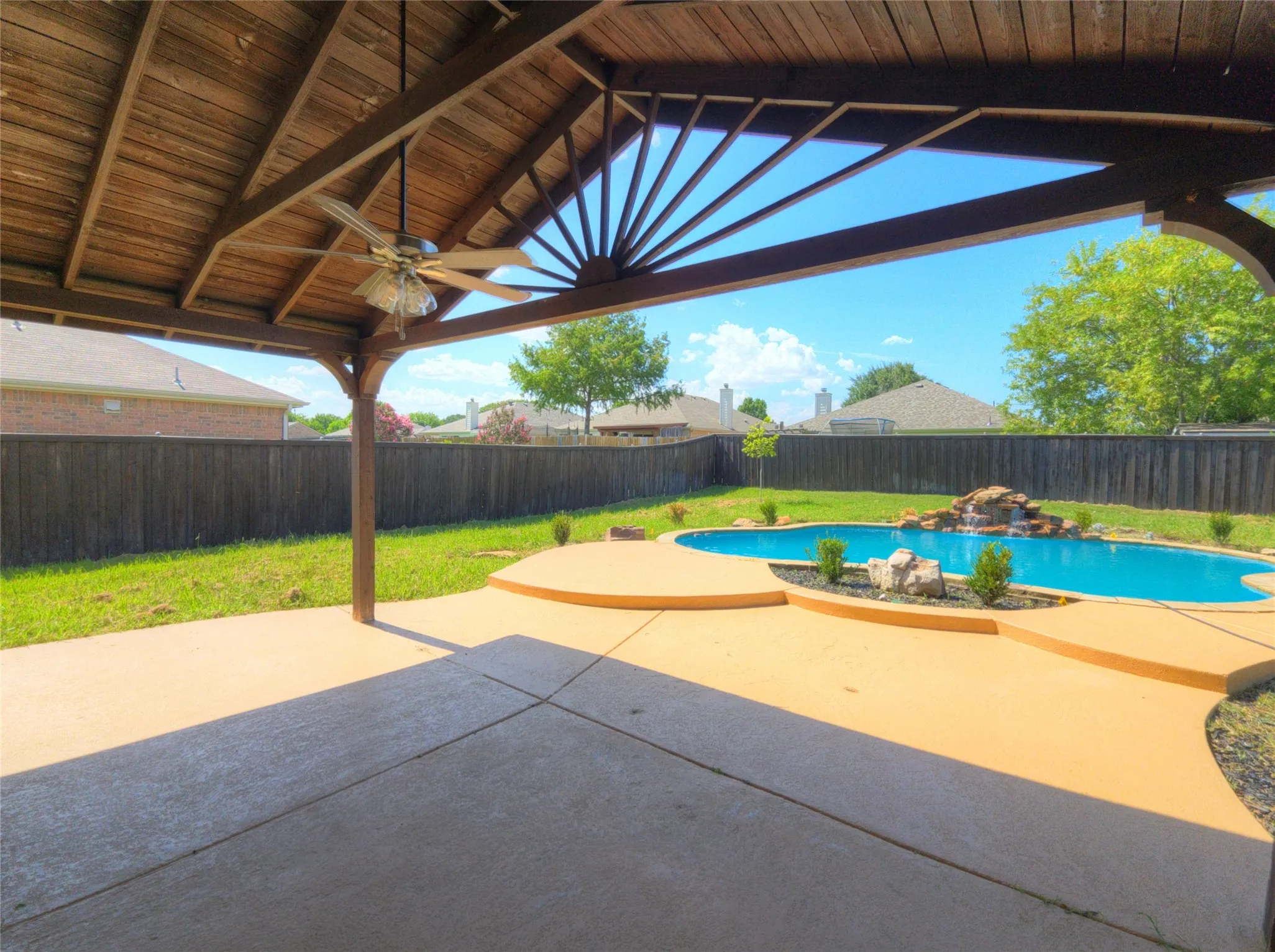 Covered patio featuring a wood-plank ceiling with integrated lighting and a ceiling fan