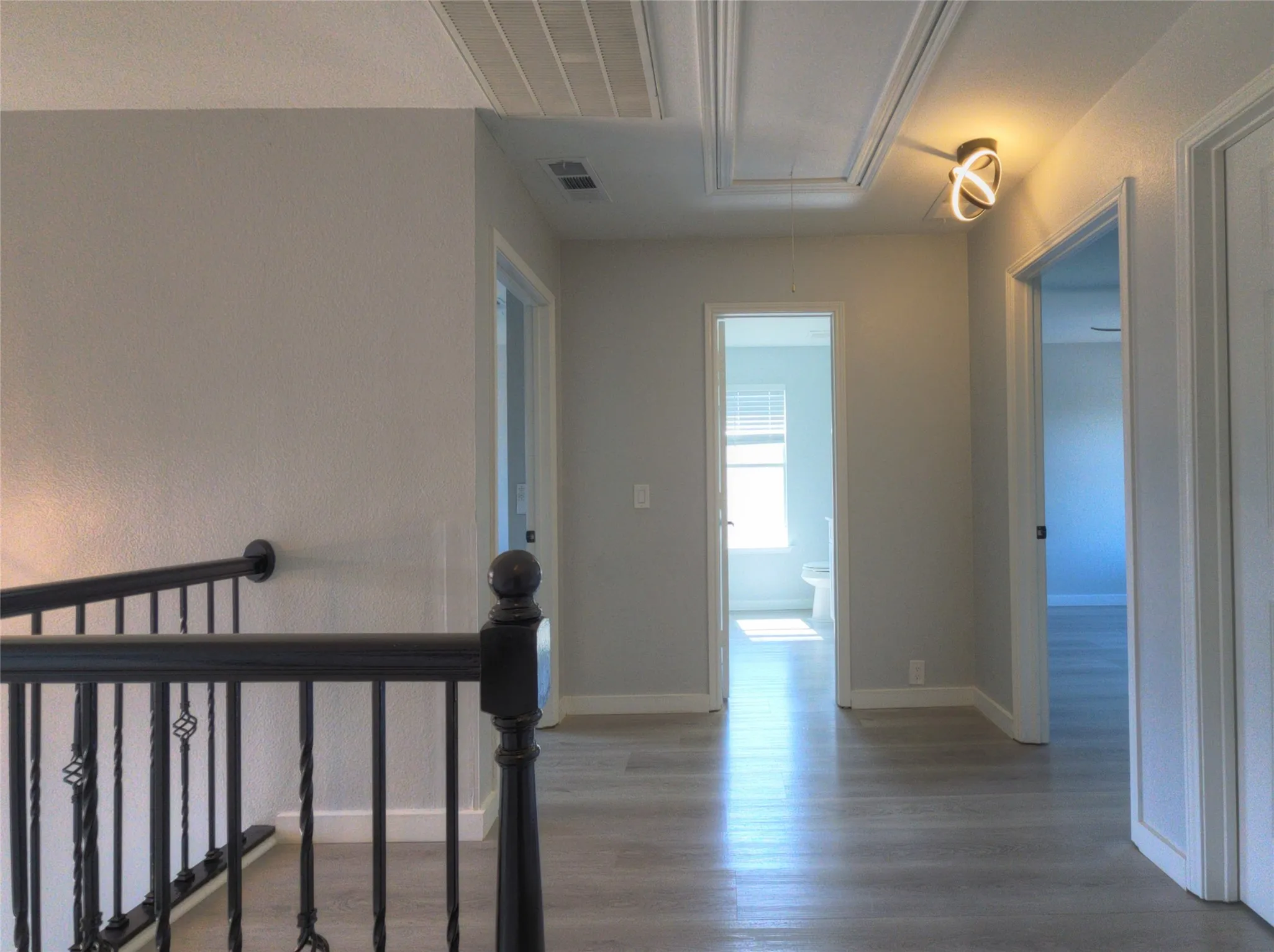 Upper level hallway featuring wood-finish flooring, light gray walls, and a contemporary ceiling fixture