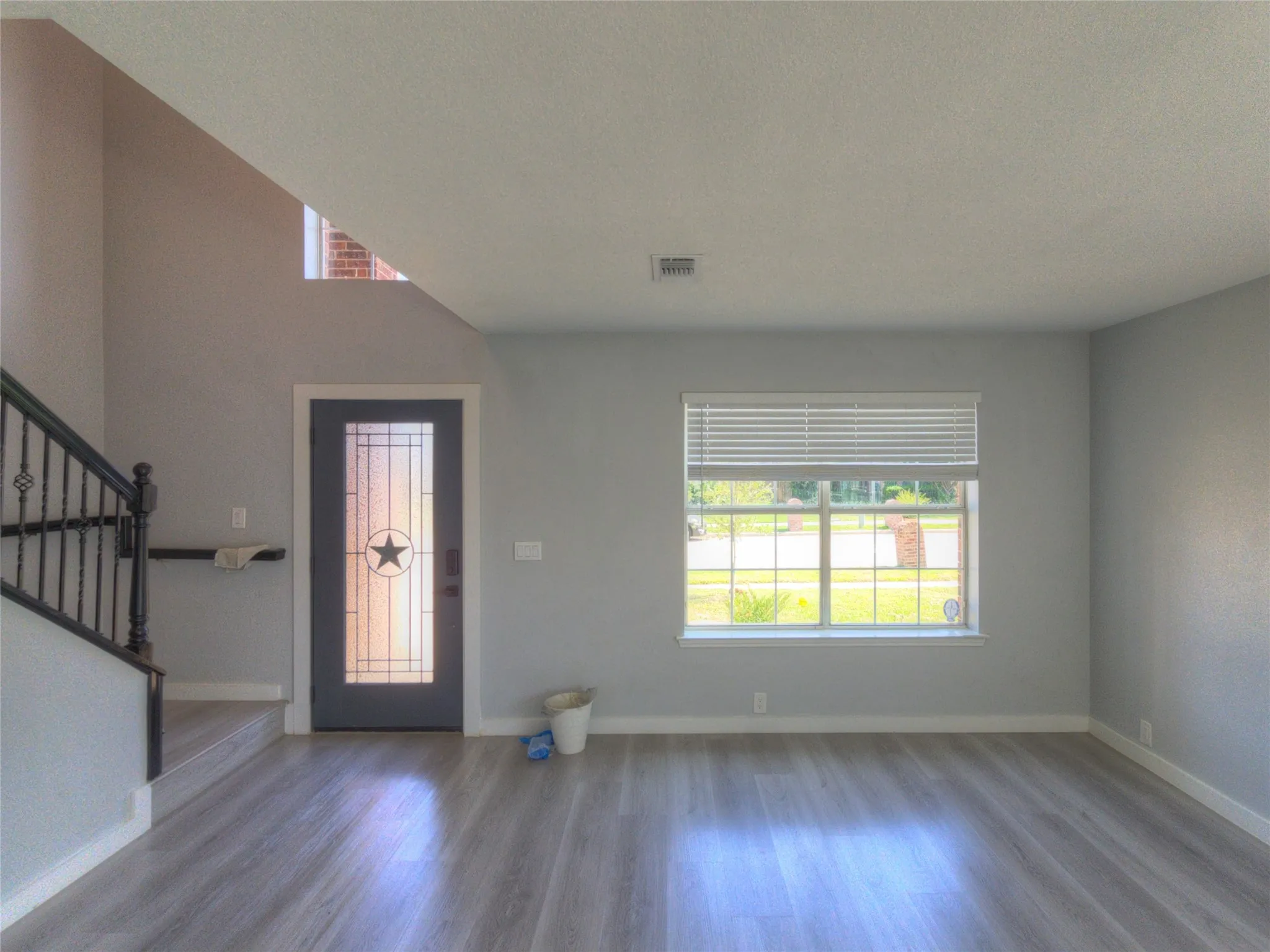 Entryway featuring a decorative glass panel door with a star motif, wood-finish flooring, and a wrought iron staircase