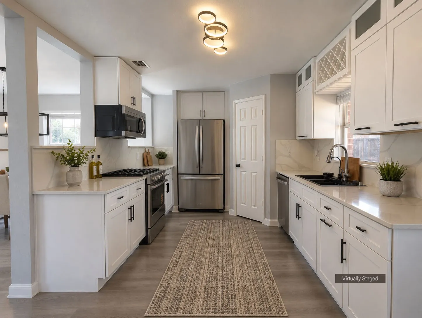 Well-appointed kitchen featuring white shaker cabinetry, stainless steel appliances, light-toned countertops, wood-finish flooring, and a contemporary ceiling light fixture