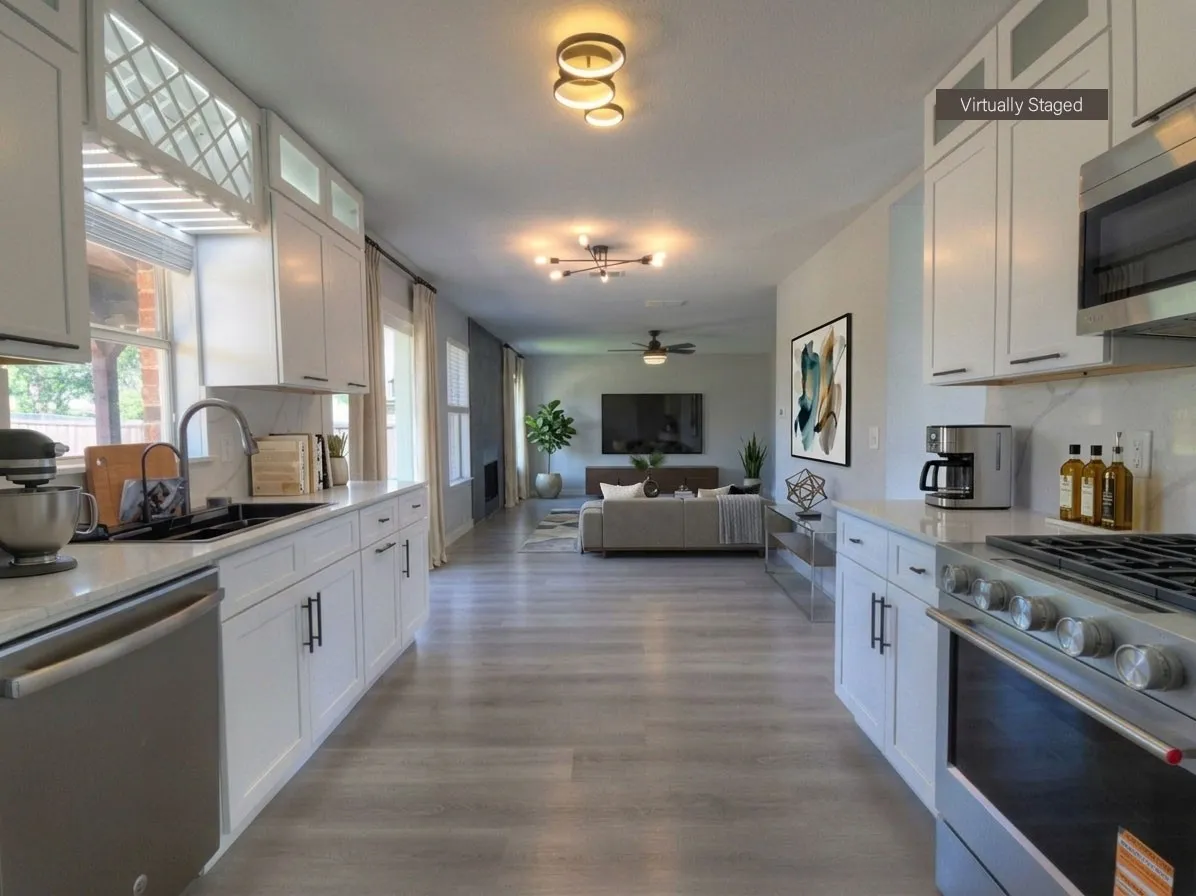 Kitchen featuring white cabinetry, light-toned countertops, stainless steel appliances, and wood-finish flooring extending into the living area