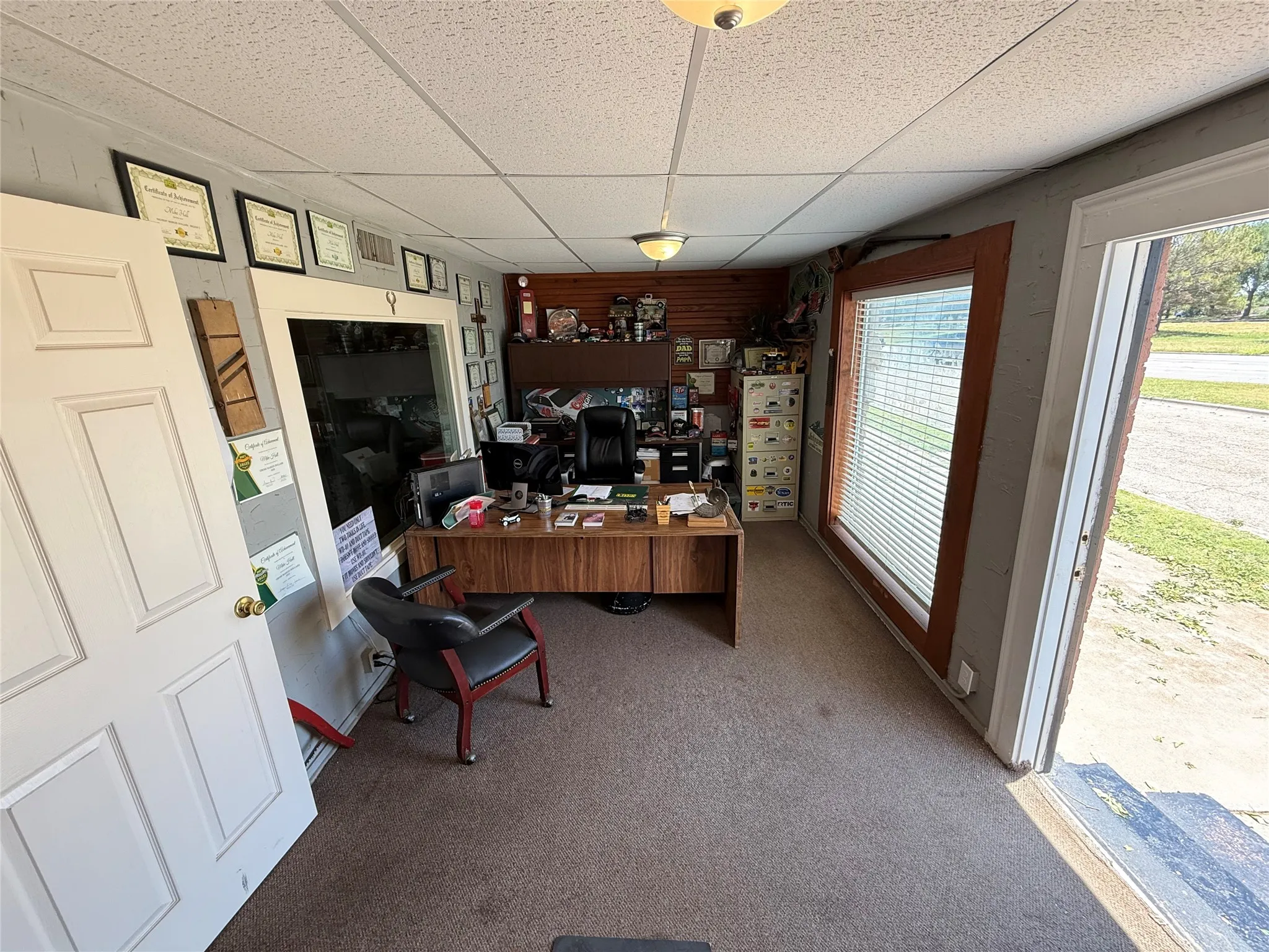 Office space featuring a large window, panel doors, drop ceiling, and carpet flooring