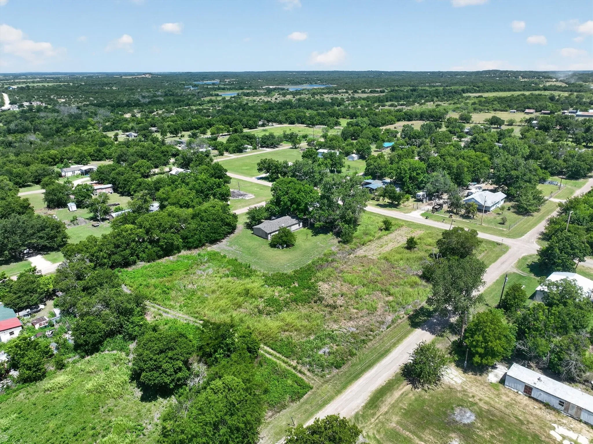 Expansive property featuring a mix of open land and mature trees, surrounded by a verdant landscape