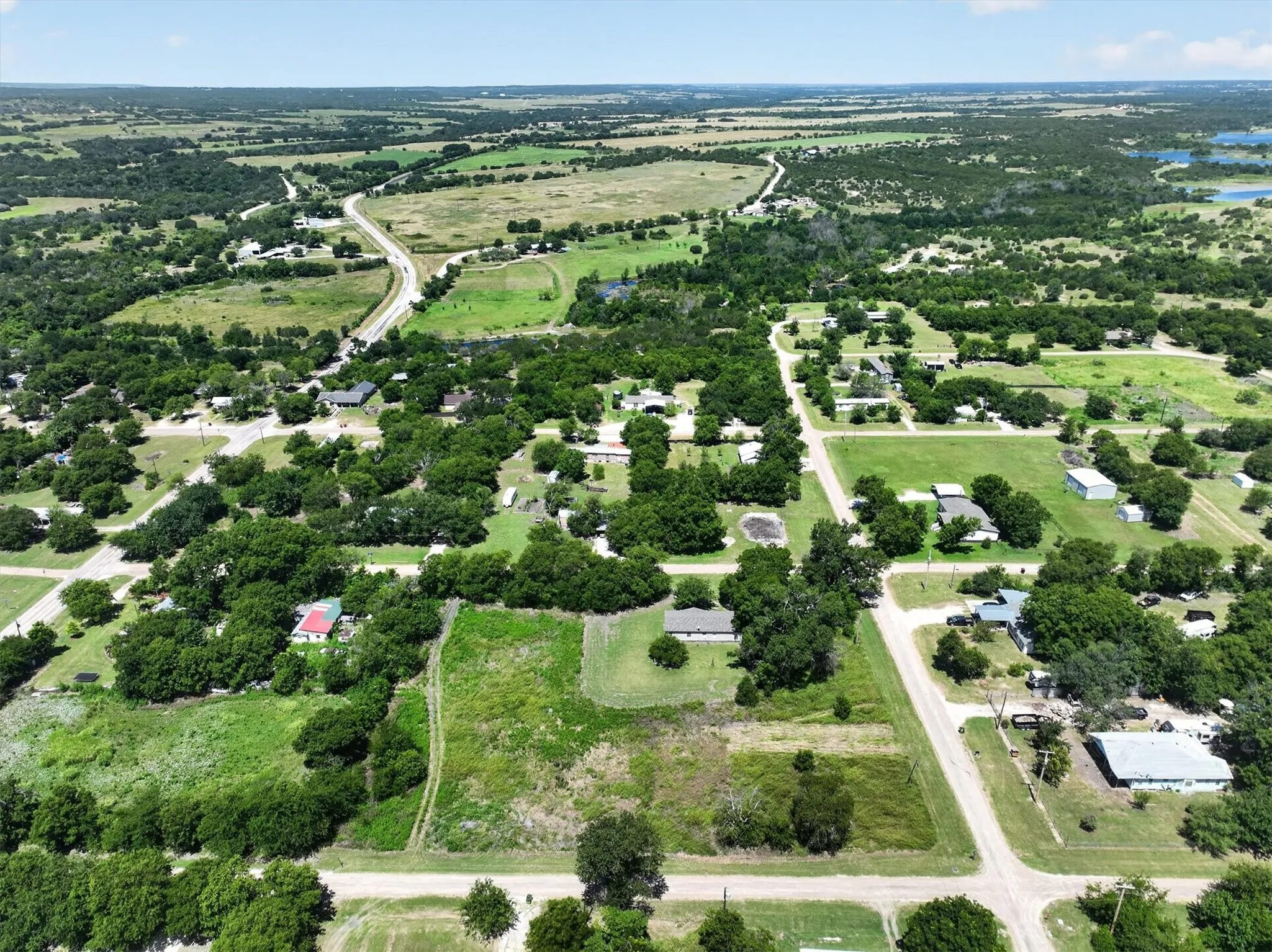 Expansive rural landscape featuring a mix of open fields, wooded areas, and scattered residential properties