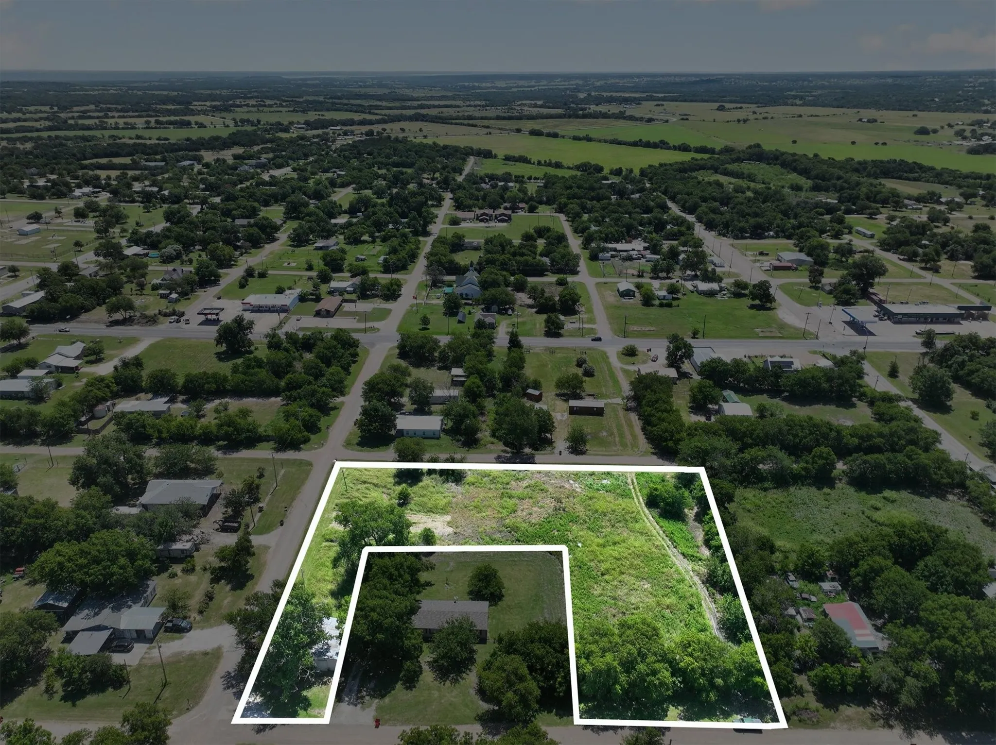 Expansive lot outlined in white, featuring mature trees and green foliage