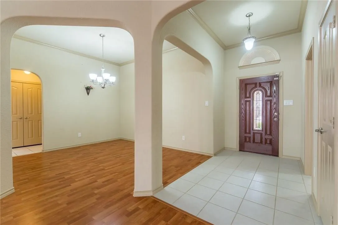 Foyer featuring a decorative front door with an arched transom window, ceramic tile flooring, and a pendant light fixture