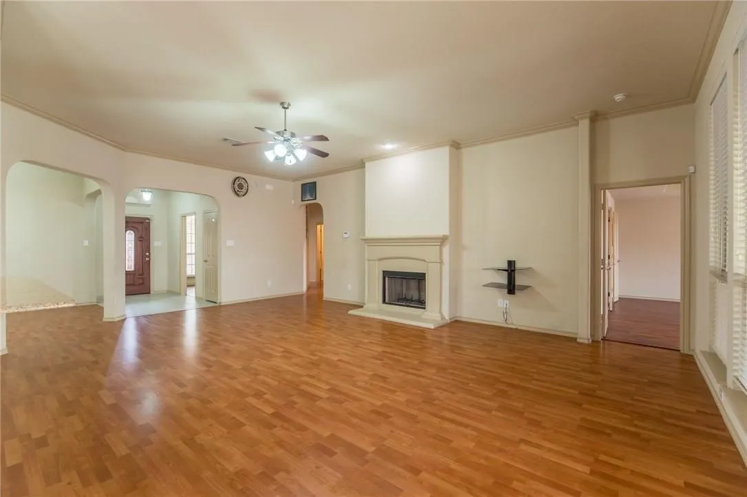 Spacious living area featuring wood-finish flooring and a ceiling fan with integrated lighting