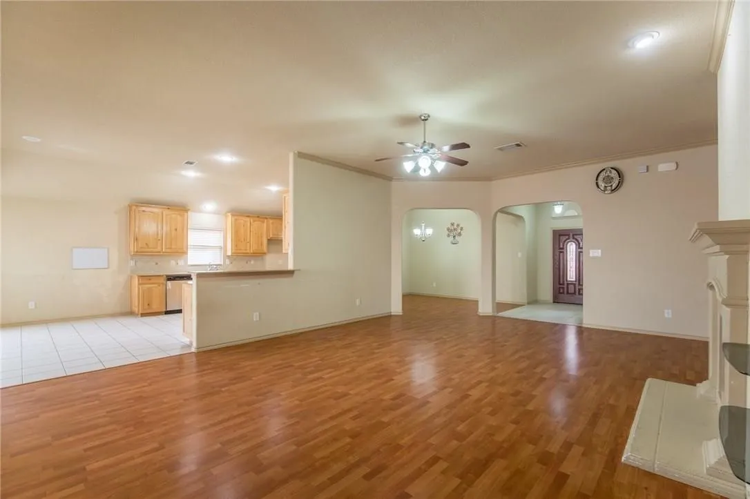 Spacious interior featuring wood-finish flooring, recessed lighting, and a prominent fireplace with a decorative mantel