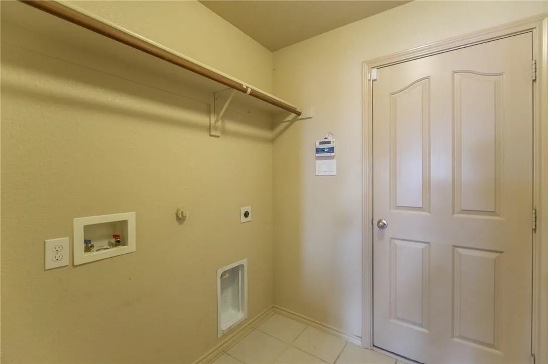 Utility area with tile flooring and a built-in hanging rod