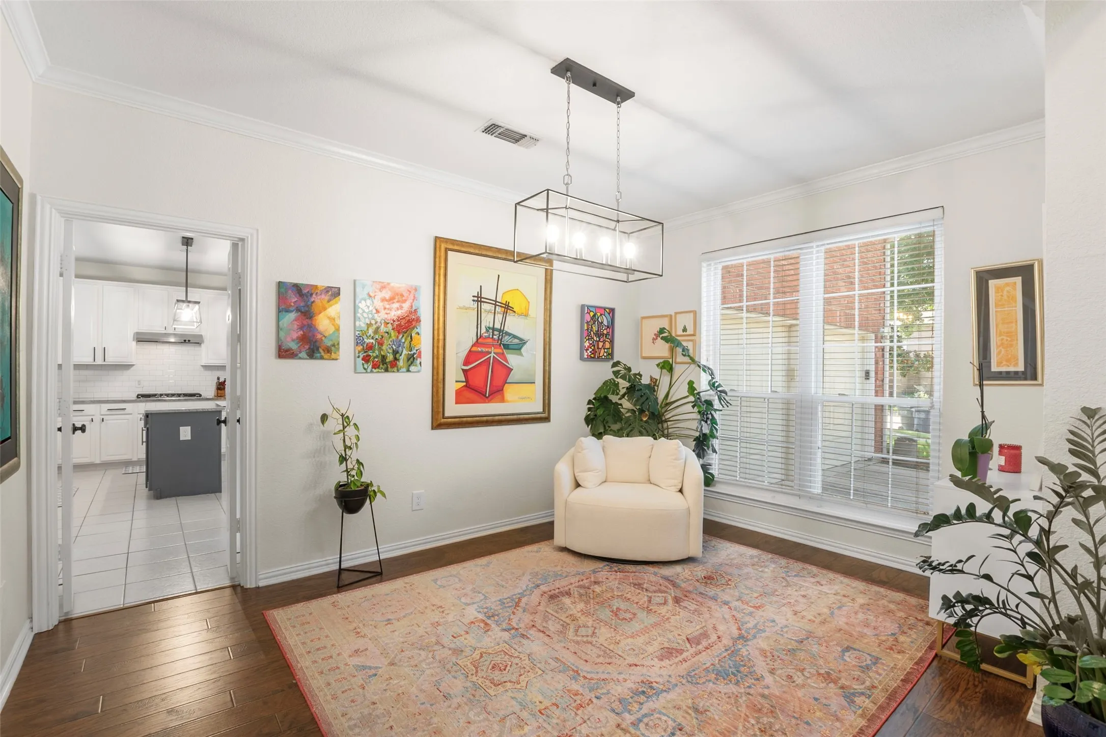 Spacious room featuring wood-finish flooring, crown molding, a large picture window, and a contemporary linear chandelier