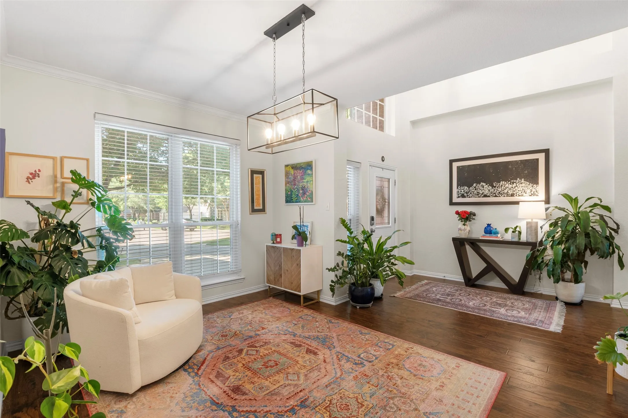 Spacious entryway featuring high ceilings, wood-finish flooring, and a large window with horizontal blinds