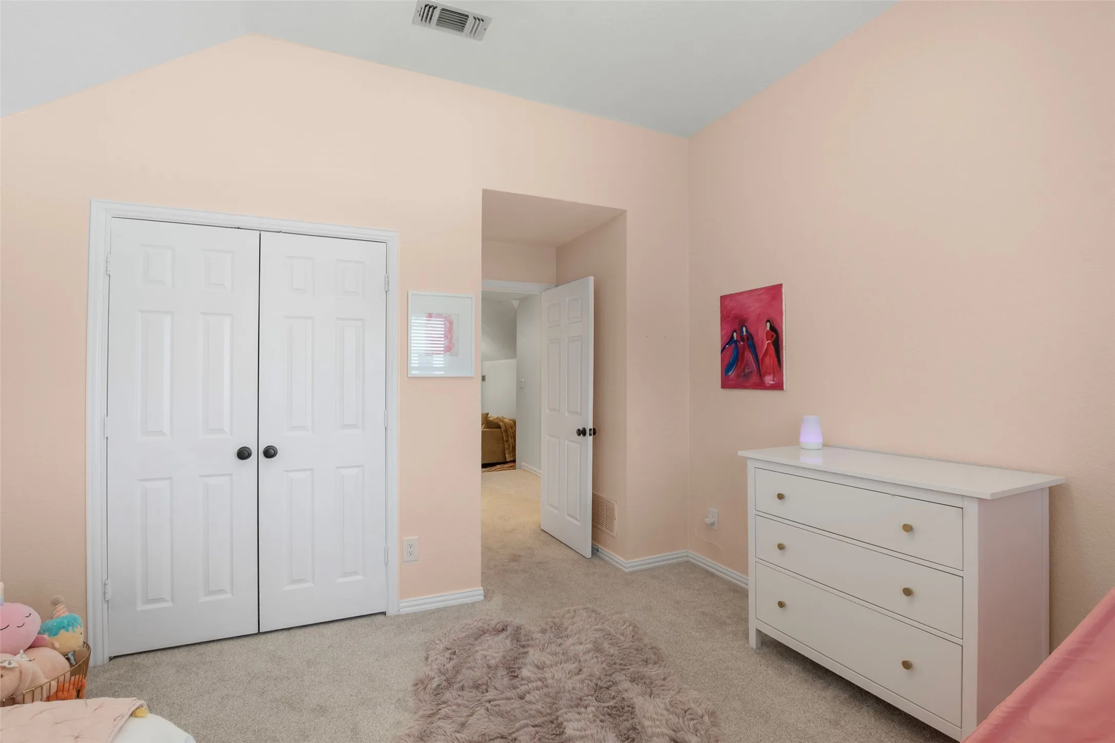 Vaulted ceiling room featuring light-toned carpeting and neutral wall tones