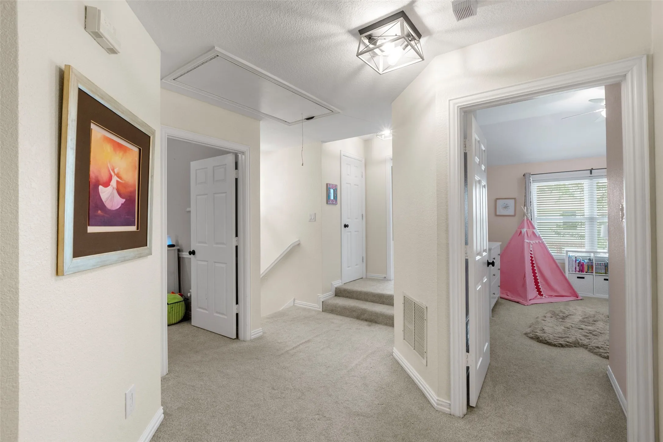 Carpeted hallway featuring a built-in access panel, a flush-mount ceiling light fixture, and white painted trim
