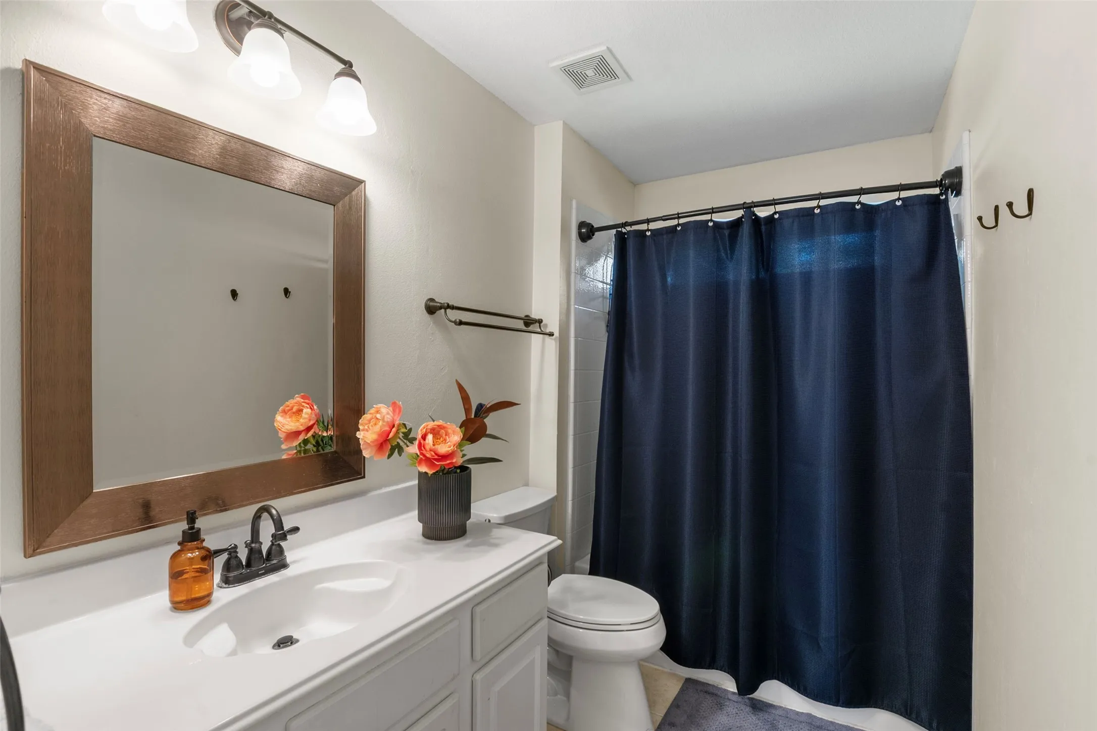 Bathroom featuring a white vanity with an integrated sink, dark bronze faucet, and a large framed mirror