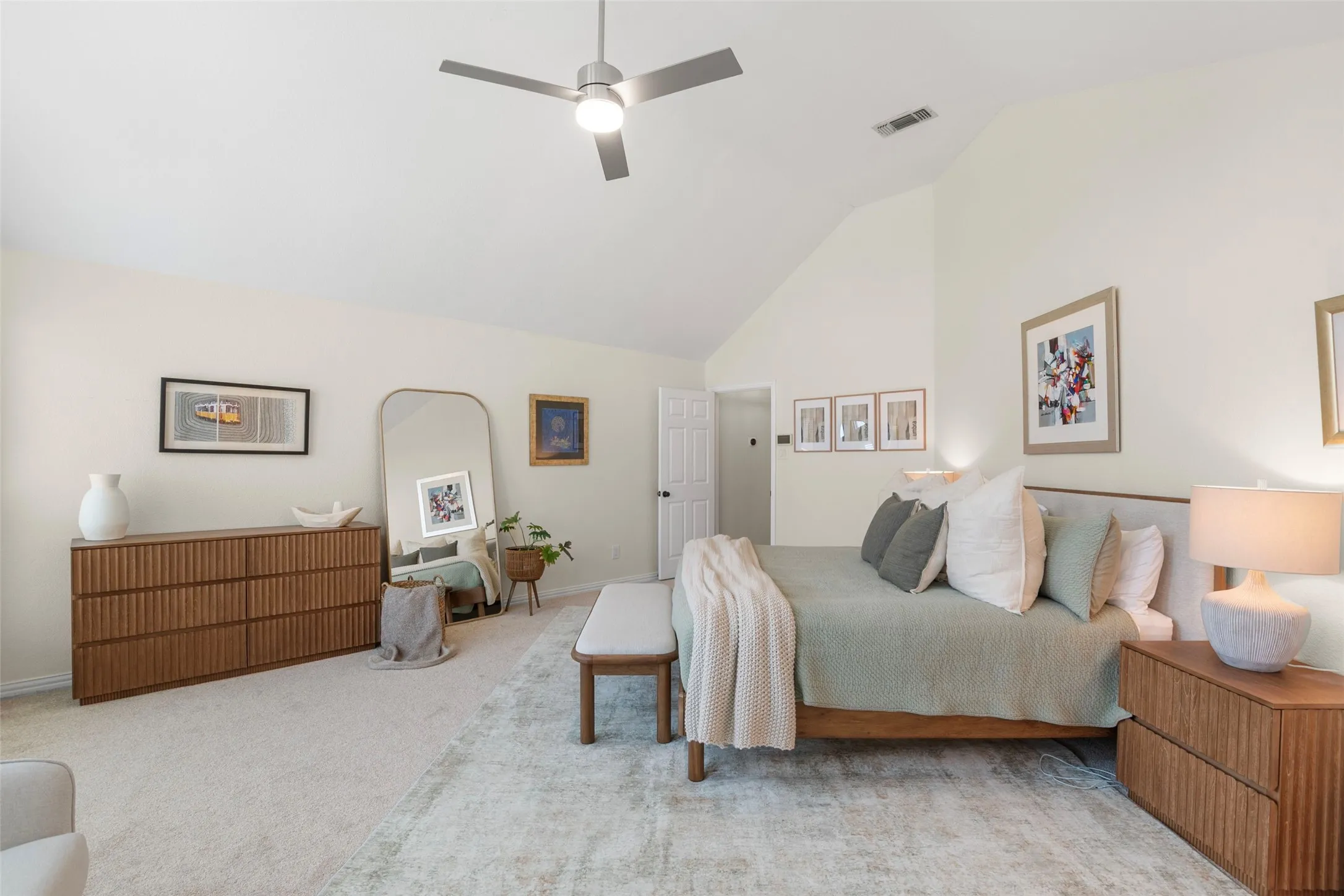 Spacious room featuring a vaulted ceiling with a ceiling fan, neutral wall tones, and plush carpeting