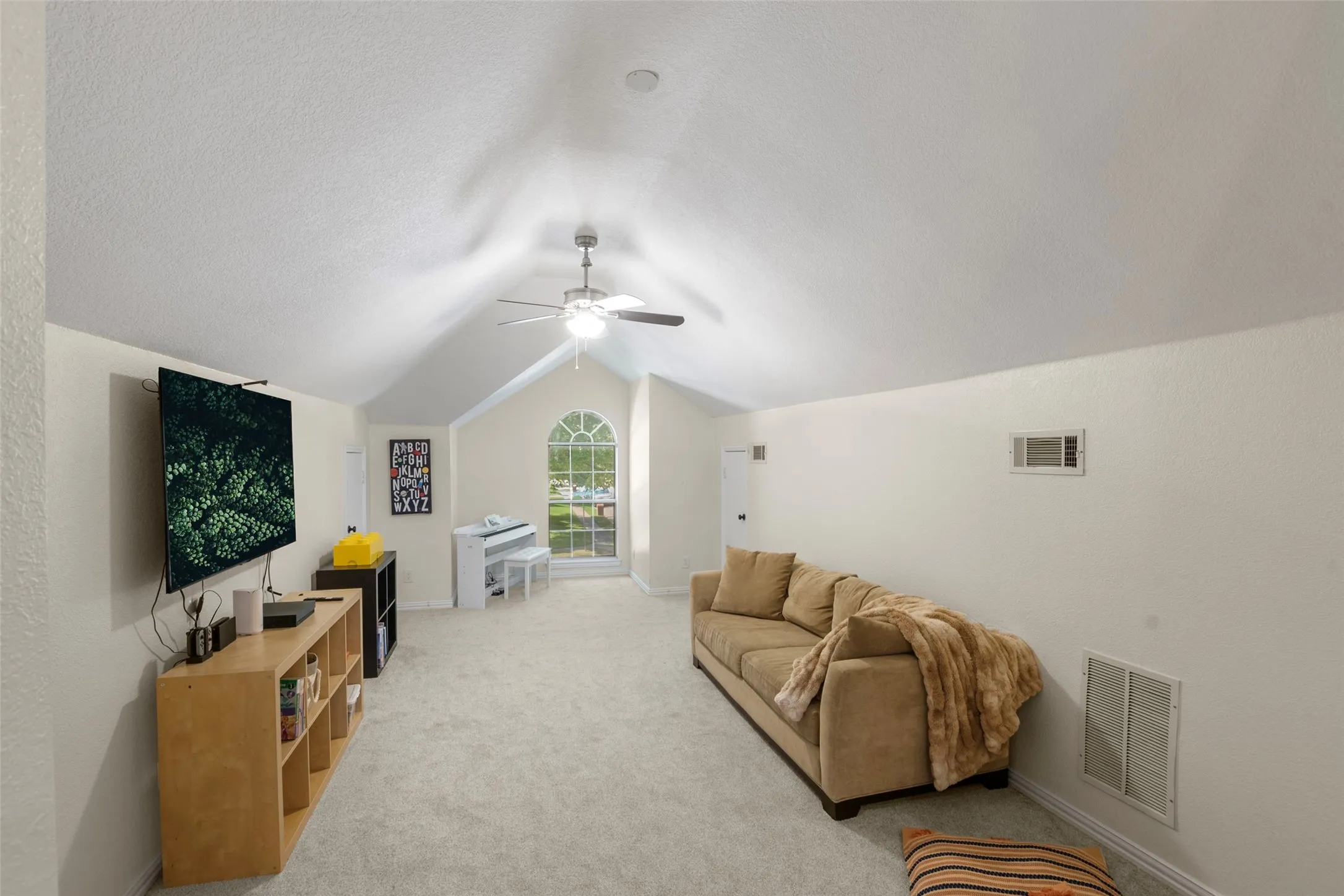 Spacious room featuring vaulted ceilings, an arched window, and plush carpeting