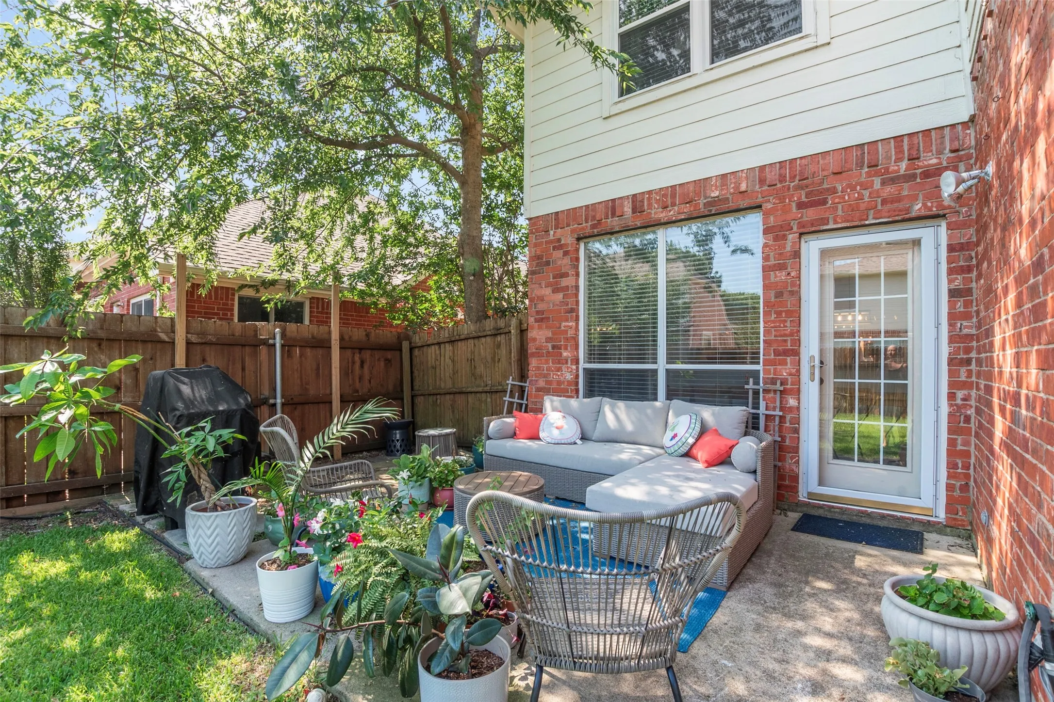 Exterior patio featuring a concrete surface, a brick facade, and a full-light door with grilles