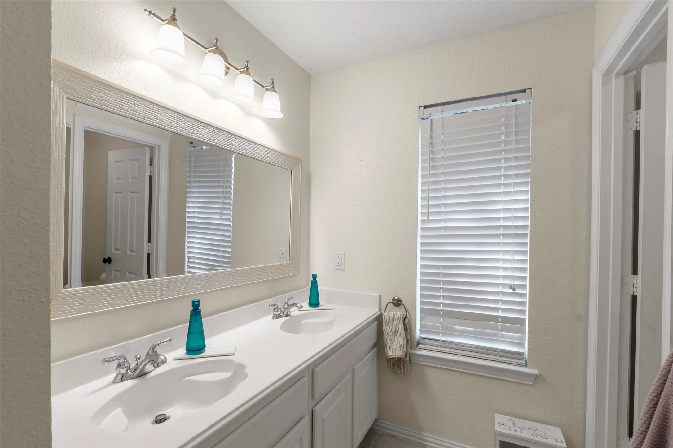 Bathroom featuring a double vanity with two sinks, a wall-mounted mirror, and overhead lighting