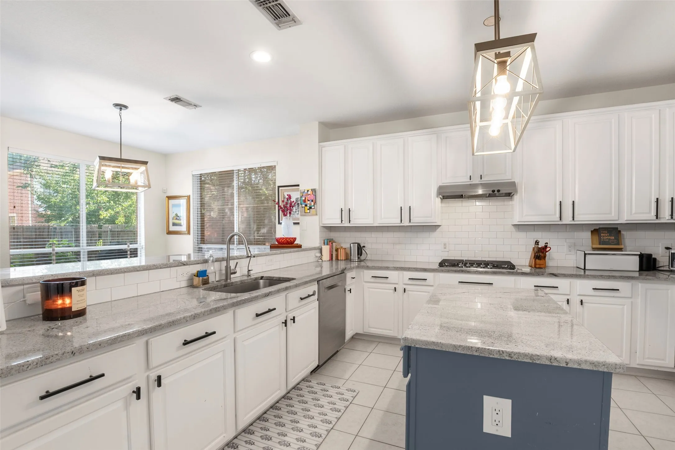 Kitchen featuring white cabinetry, light-colored countertops, subway tile backsplash, a center island with contrasting base, and stainless steel appliances