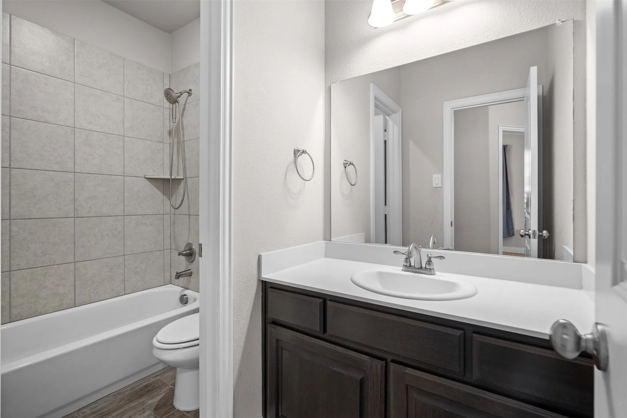 Bathroom featuring a dark wood-finish vanity with a white countertop, an undermount sink, and a large wall-mounted mirror