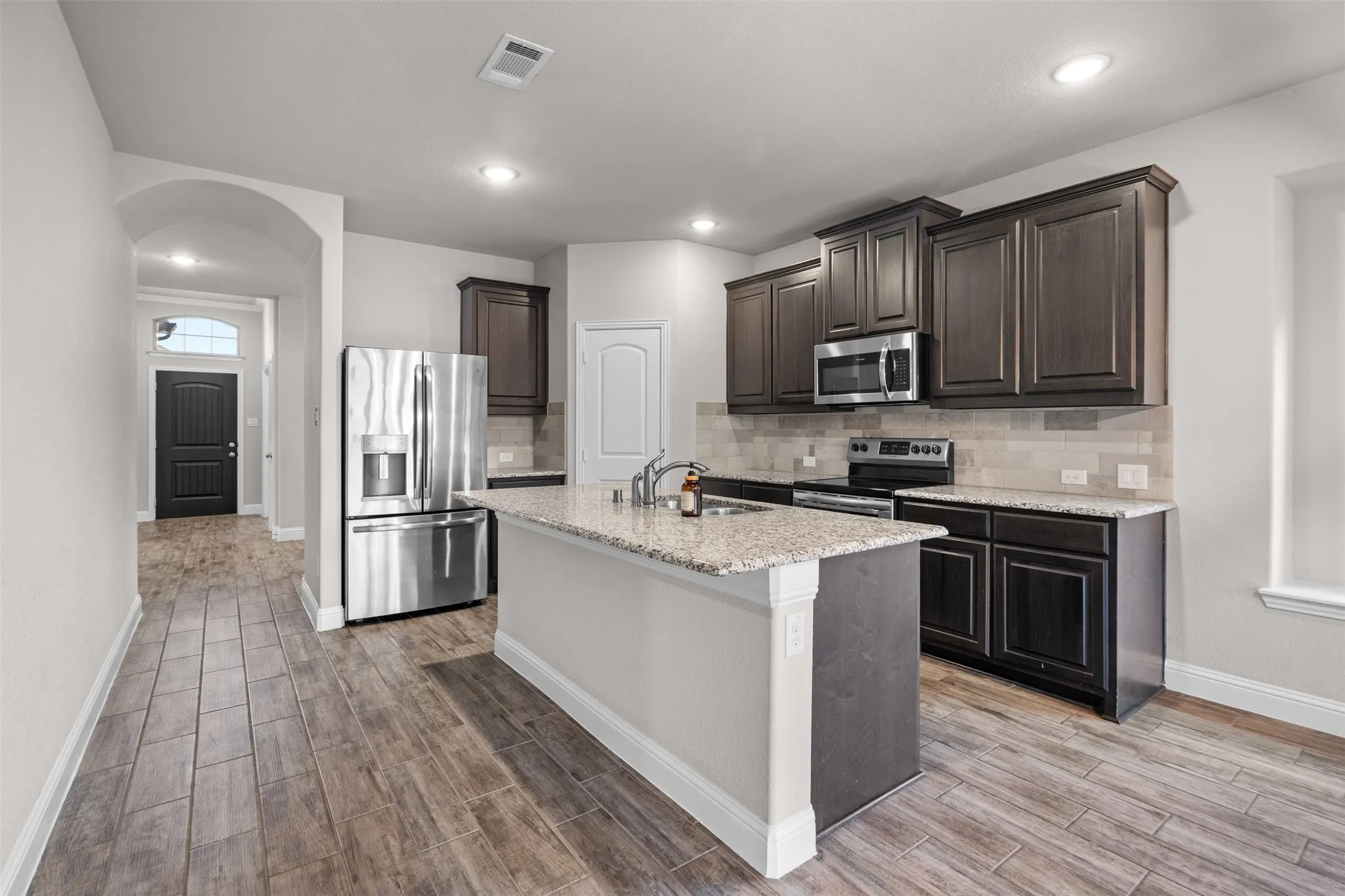 Contemporary kitchen featuring a center island, dark wood cabinetry, stainless steel appliances, and tile flooring
