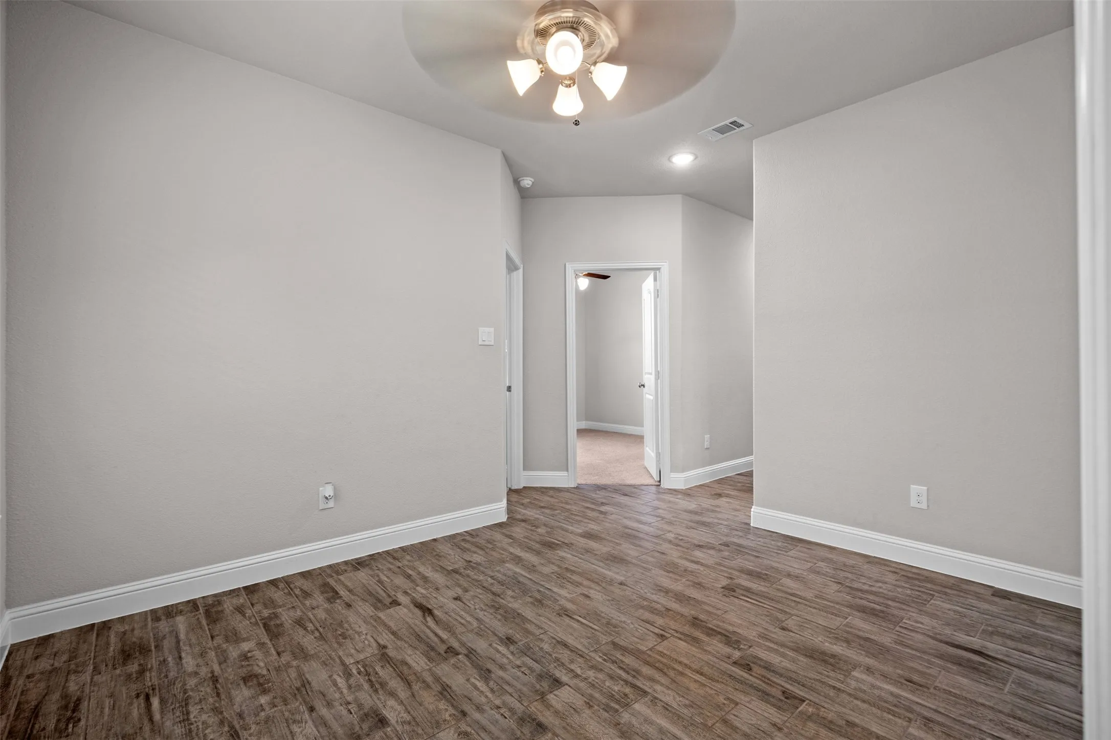 Interior space featuring wood-finish flooring, light neutral wall paint, and white baseboards