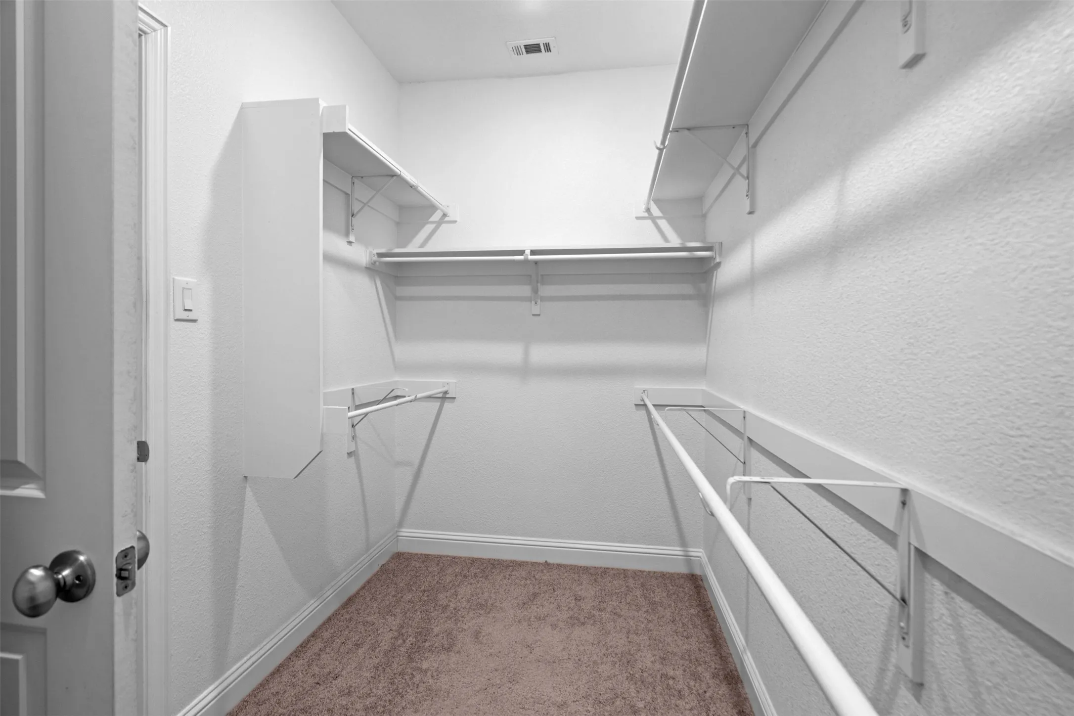 Walk-in closet featuring built-in shelving, hanging rods, and carpet flooring
