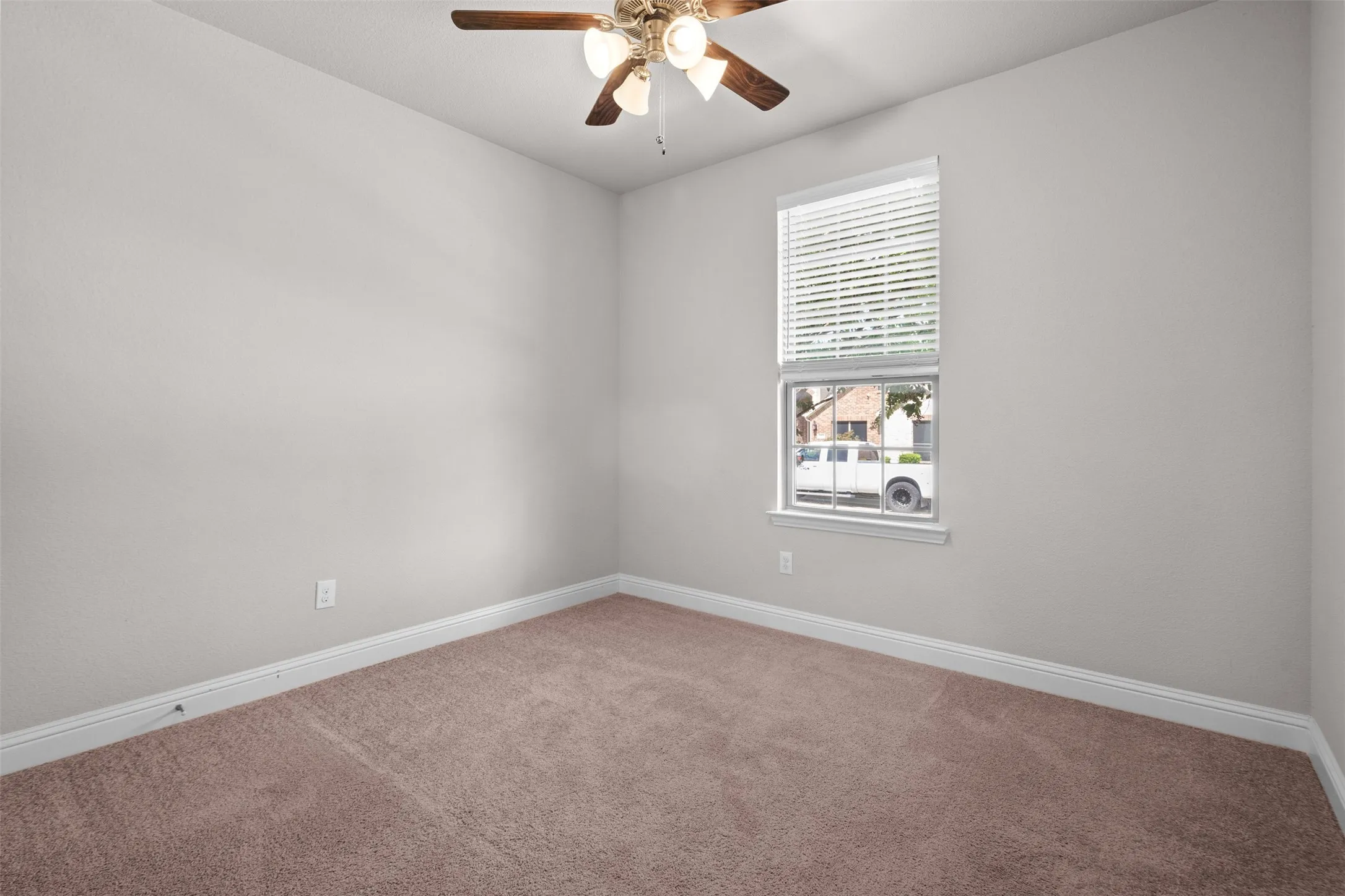 Neutral-toned wall finishes featuring a single window with blinds, a ceiling fan with light fixture, and brown carpet flooring