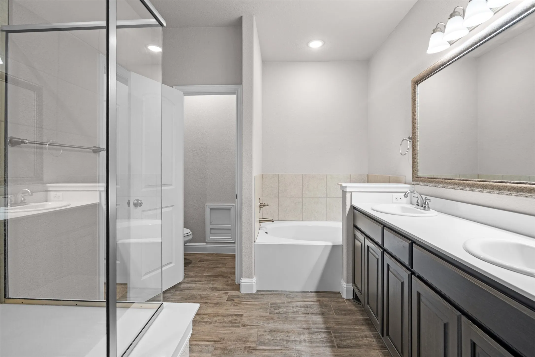Bathroom featuring a double vanity with white countertops, dark wood-finish cabinetry, and a framed mirror