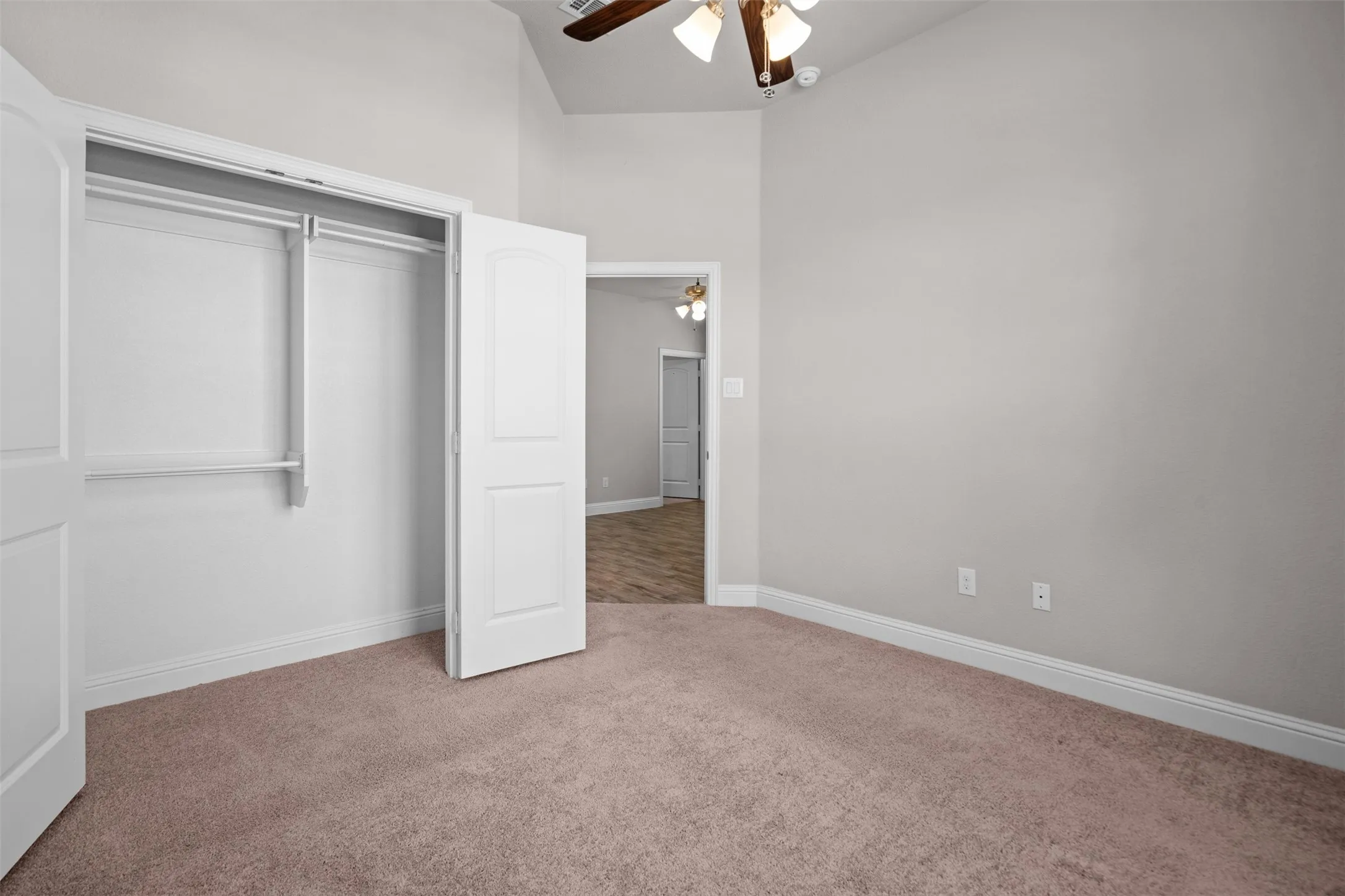 Carpeted room featuring a double-door closet with shelving and hanging rods
