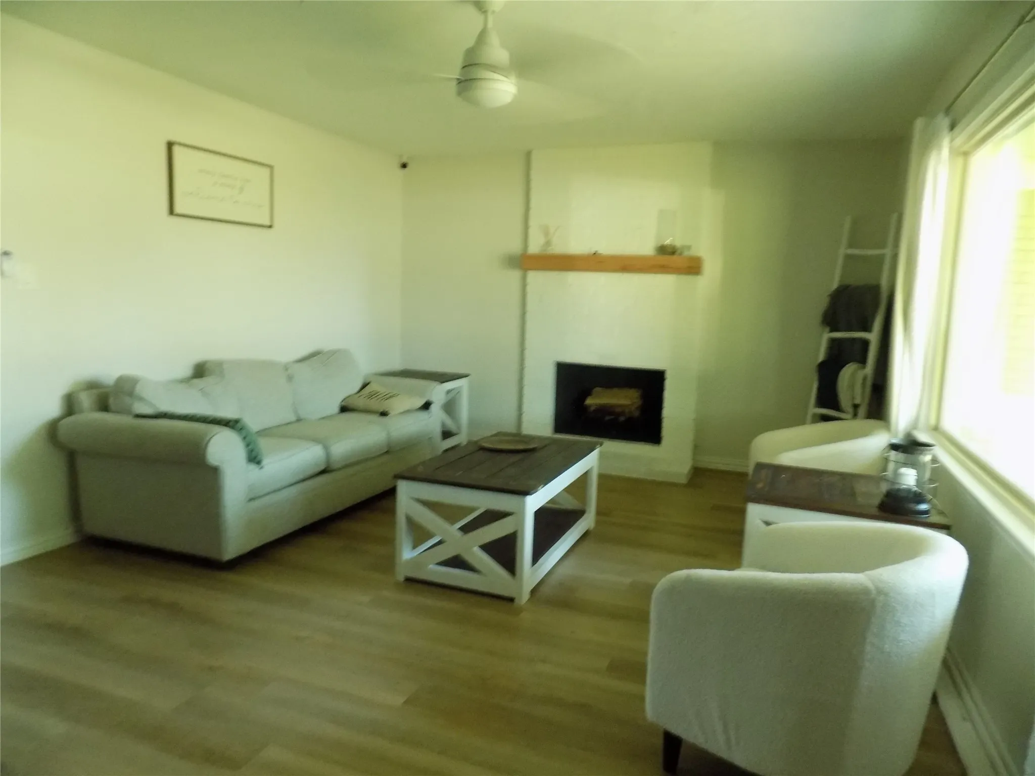 Well, beautifully lit living room with fireplace and picture window.