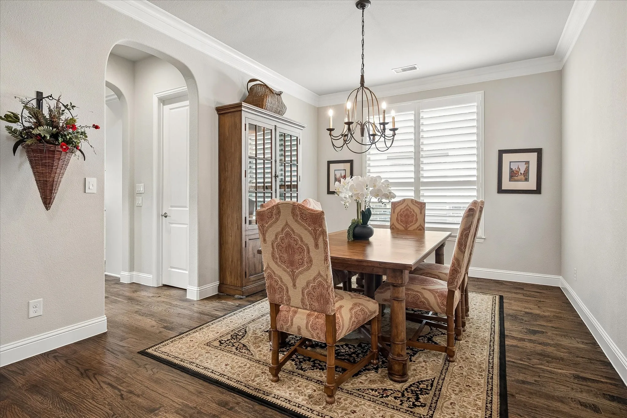 Dining area featuring wood-finish flooring, an arched doorway, and crown molding