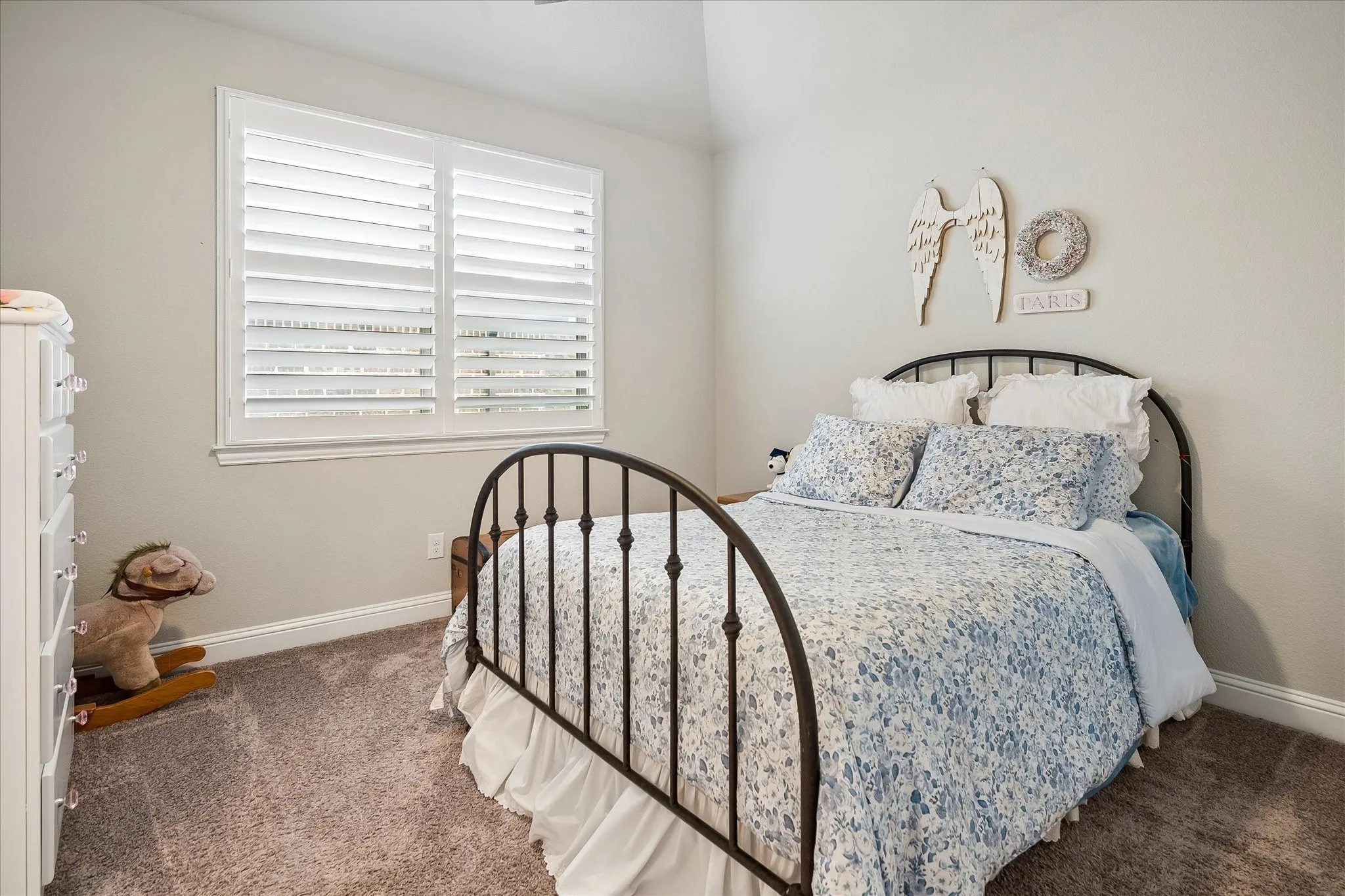 Bedroom featuring a window with white plantation shutters, neutral wall paint, white baseboards, and carpet flooring