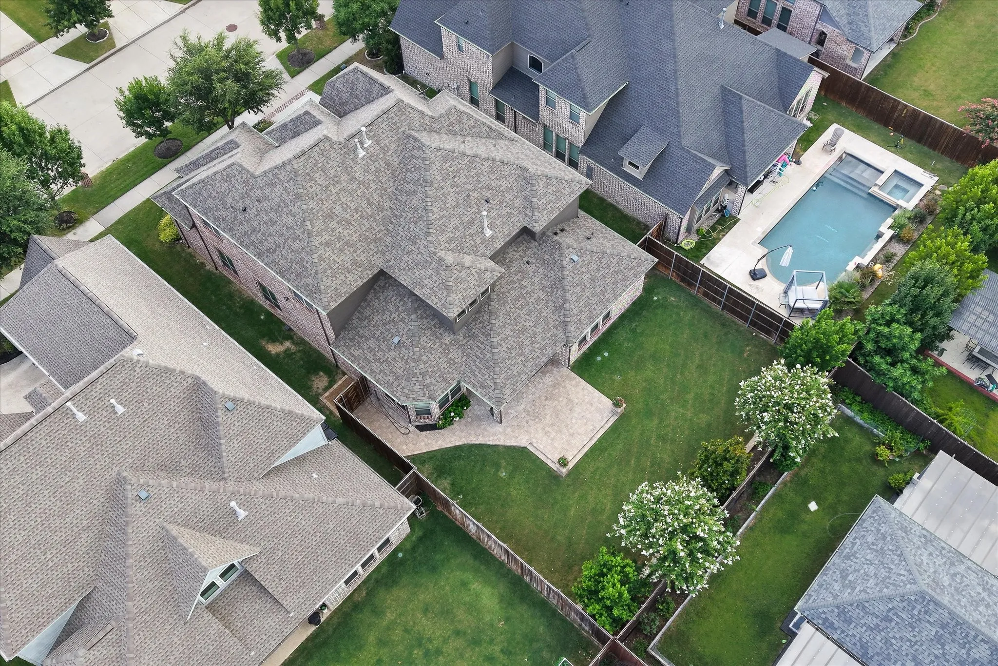 Spacious backyard featuring a manicured lawn, paved patio, and mature landscaping