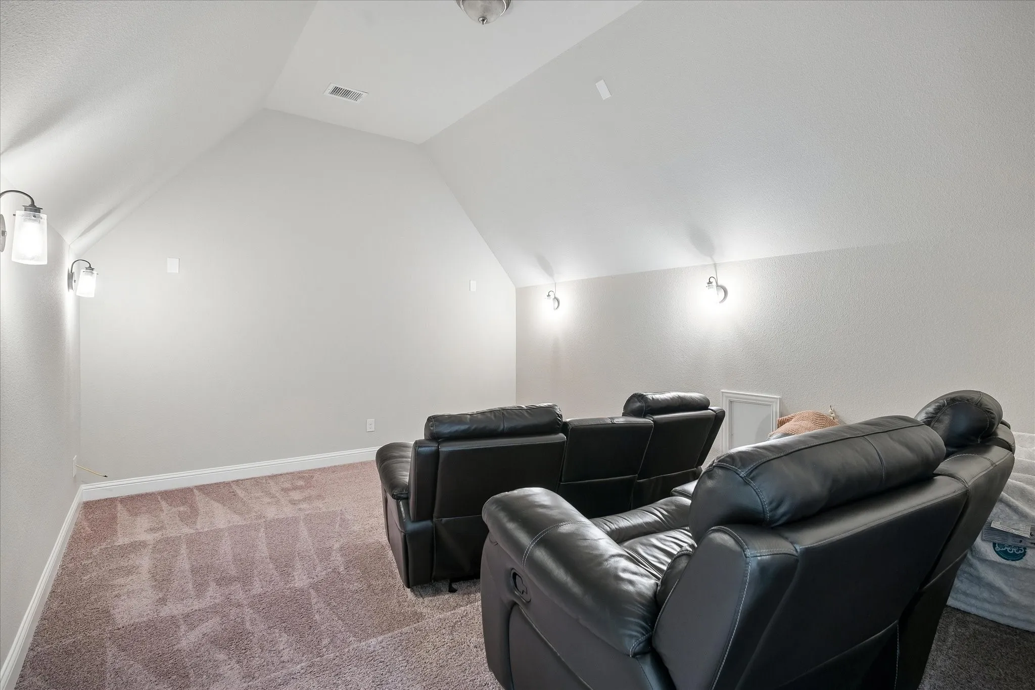 Carpeted bonus room featuring sloped ceilings and wall-mounted sconces