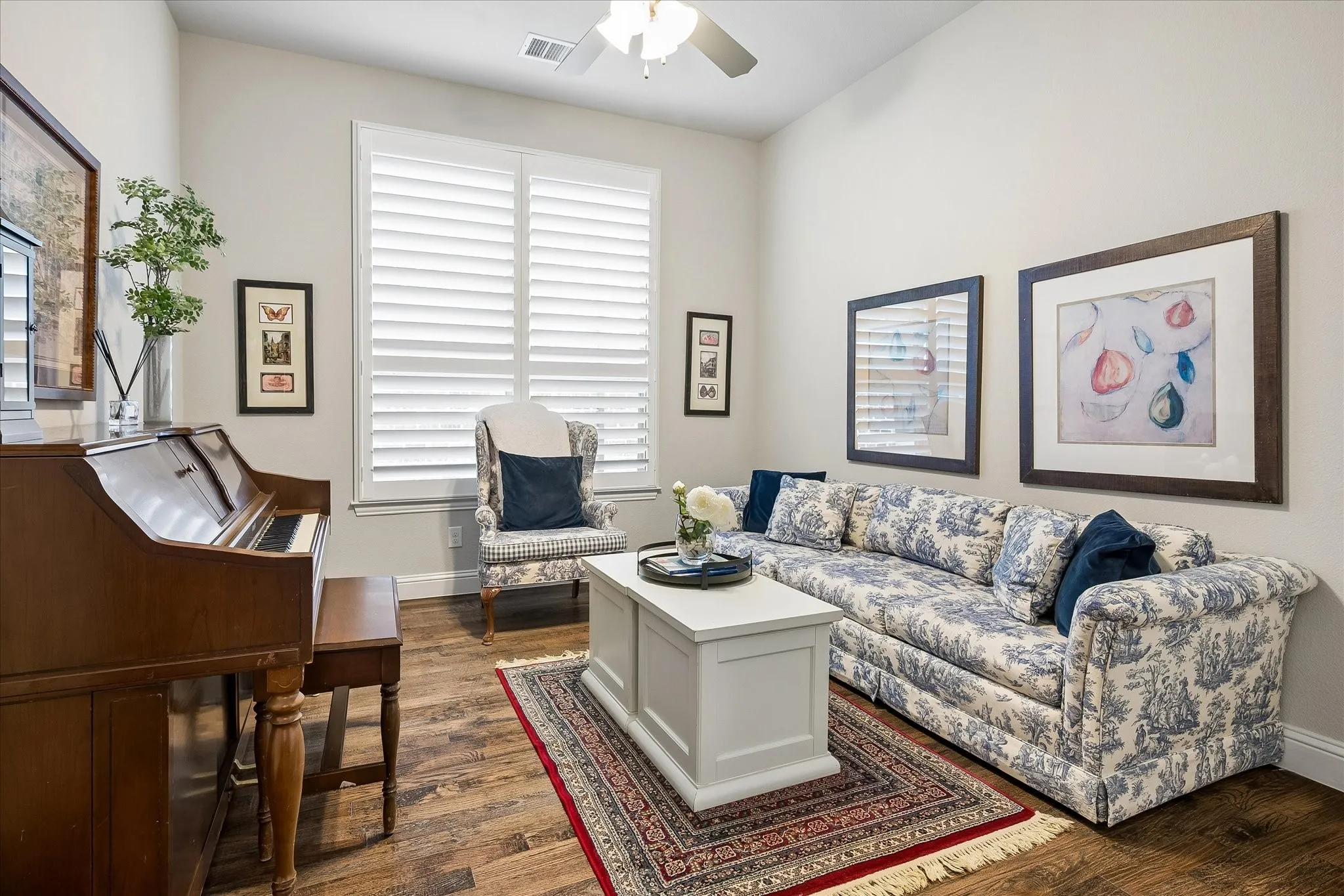 Living area featuring a stone-clad fireplace with a wood mantel, multi-paned windows with plantation shutters, high ceilings, and wood-finish flooring