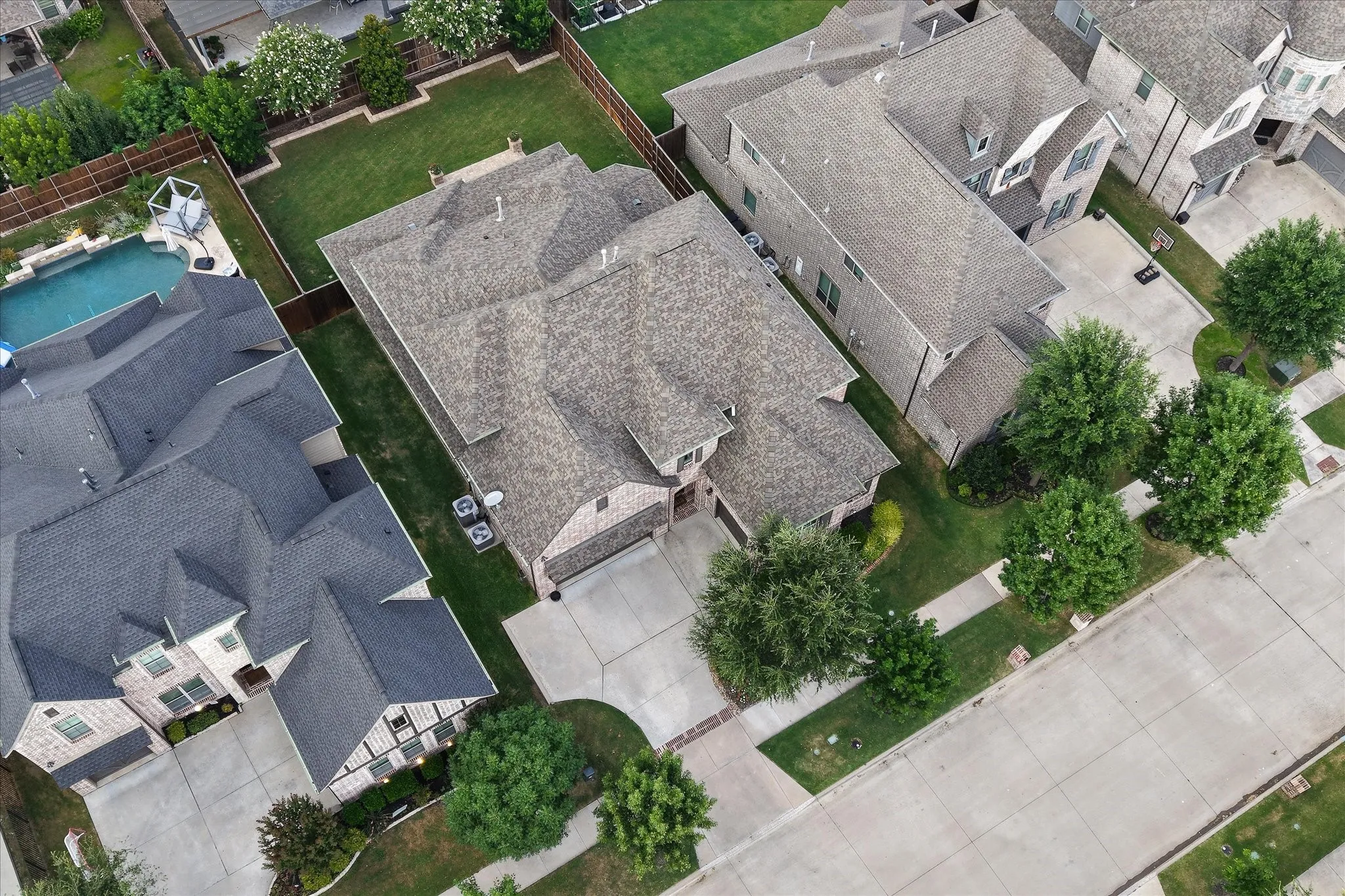 Gable roofline residence featuring a two-car garage, concrete driveway, and mature landscaping