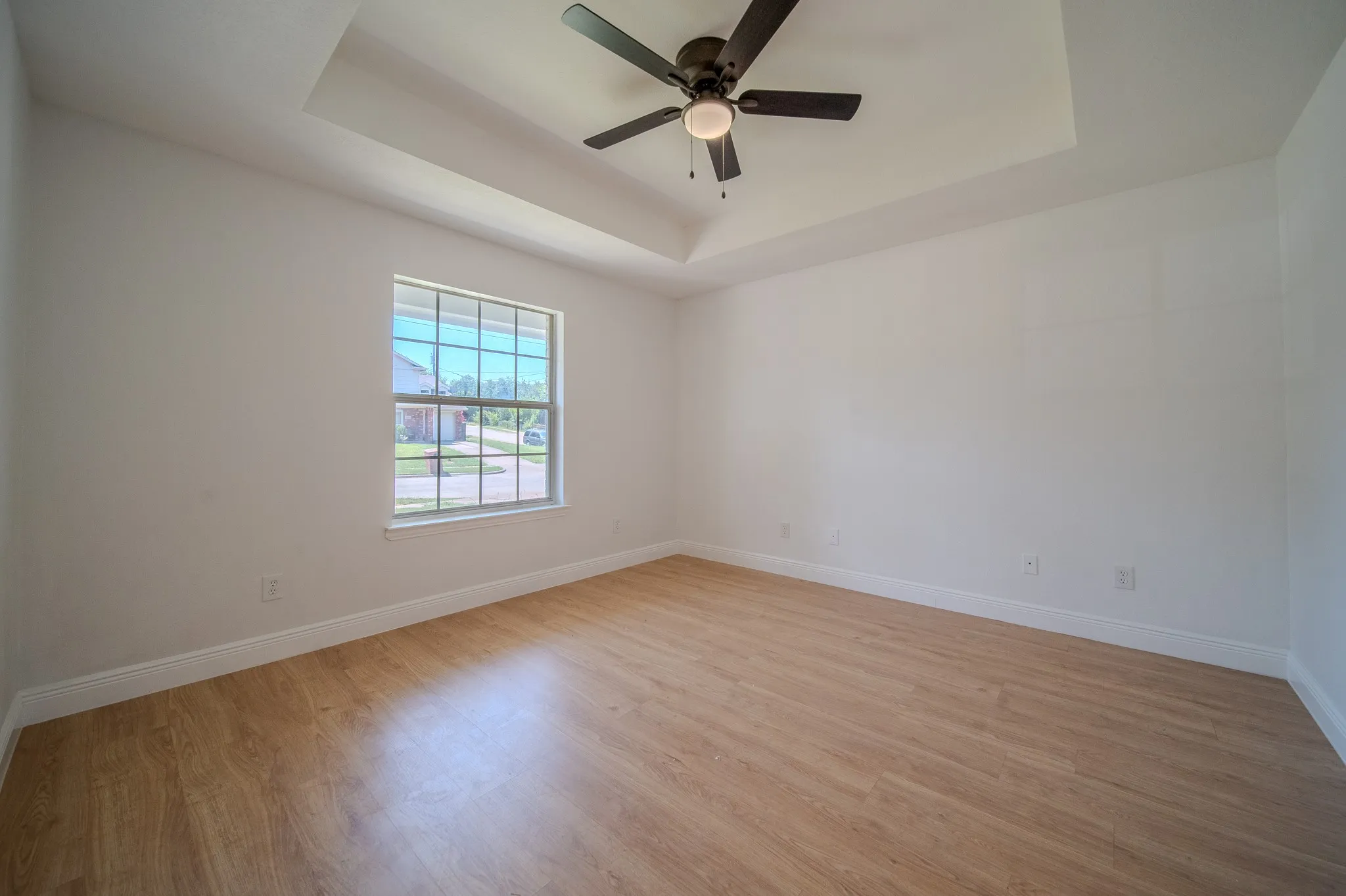 Spacious room with a tray ceiling and a ceiling fan