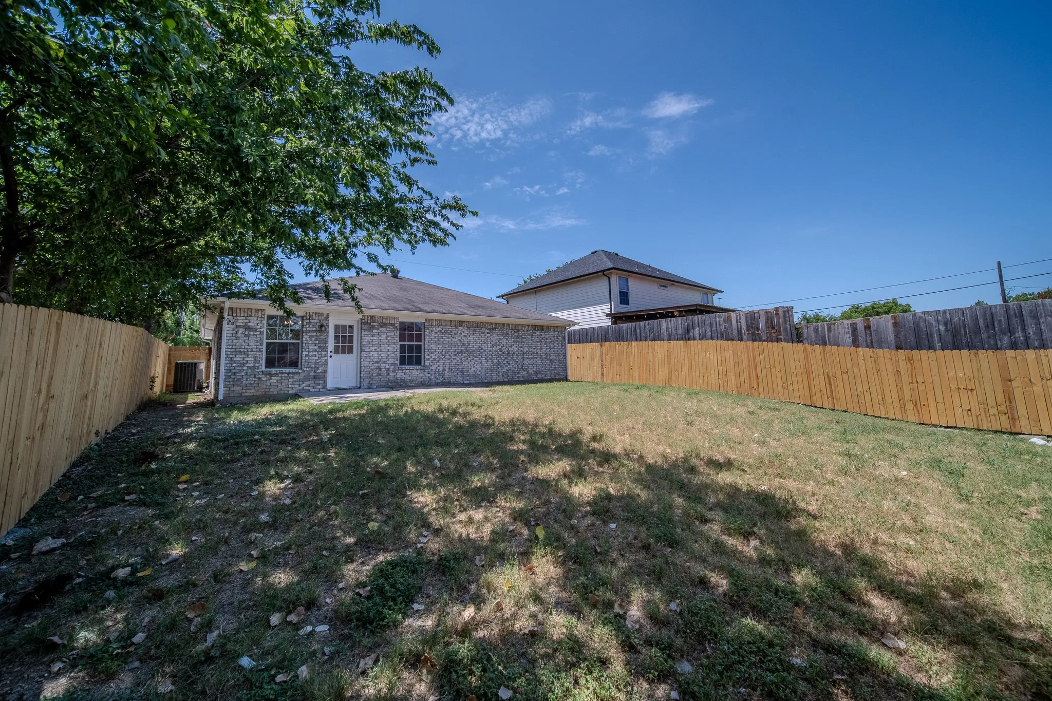 Expansive backyard featuring a partial new wood privacy fence