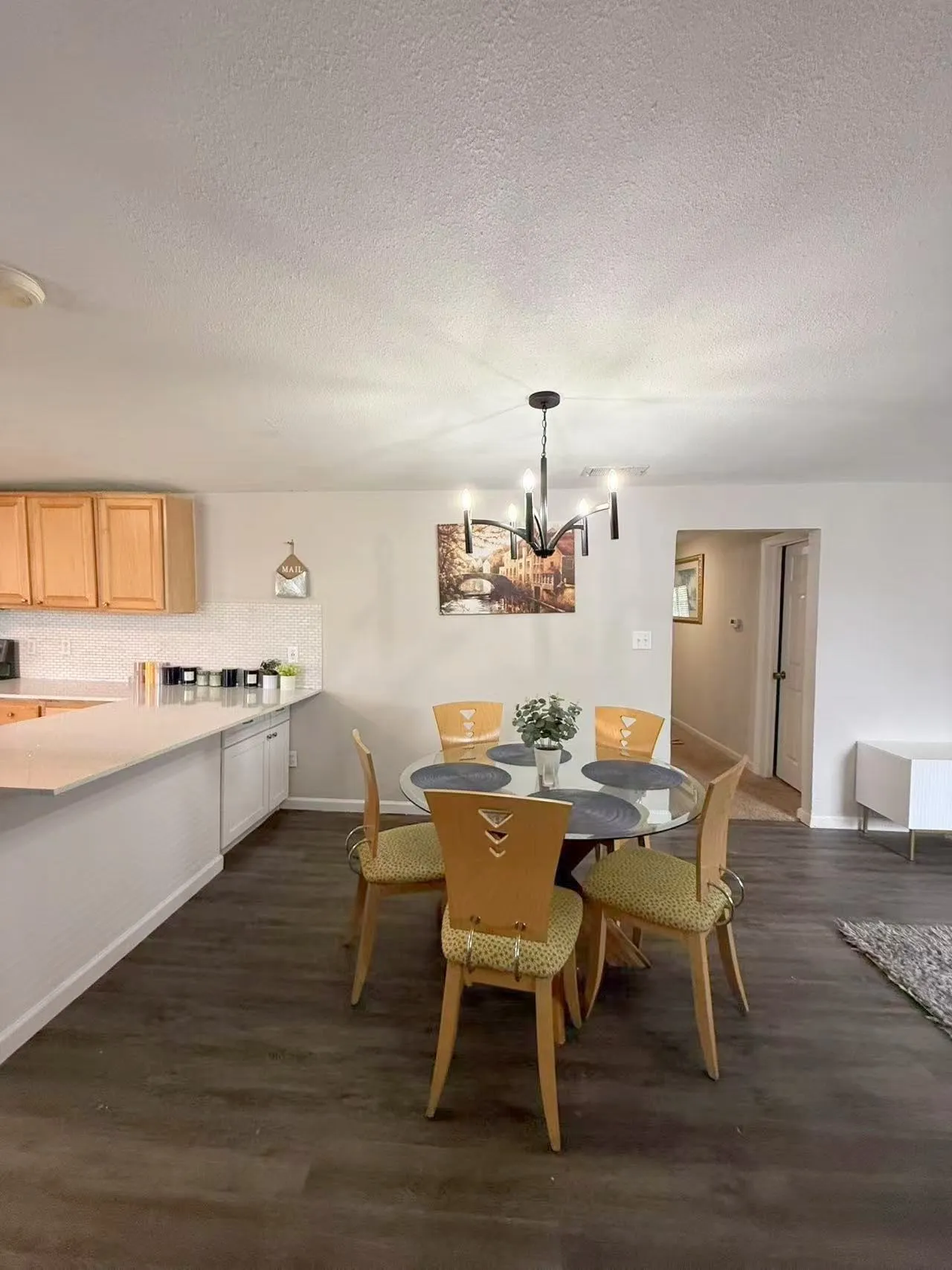 Open-concept dining area featuring wood-finish flooring and a contemporary chandelier
