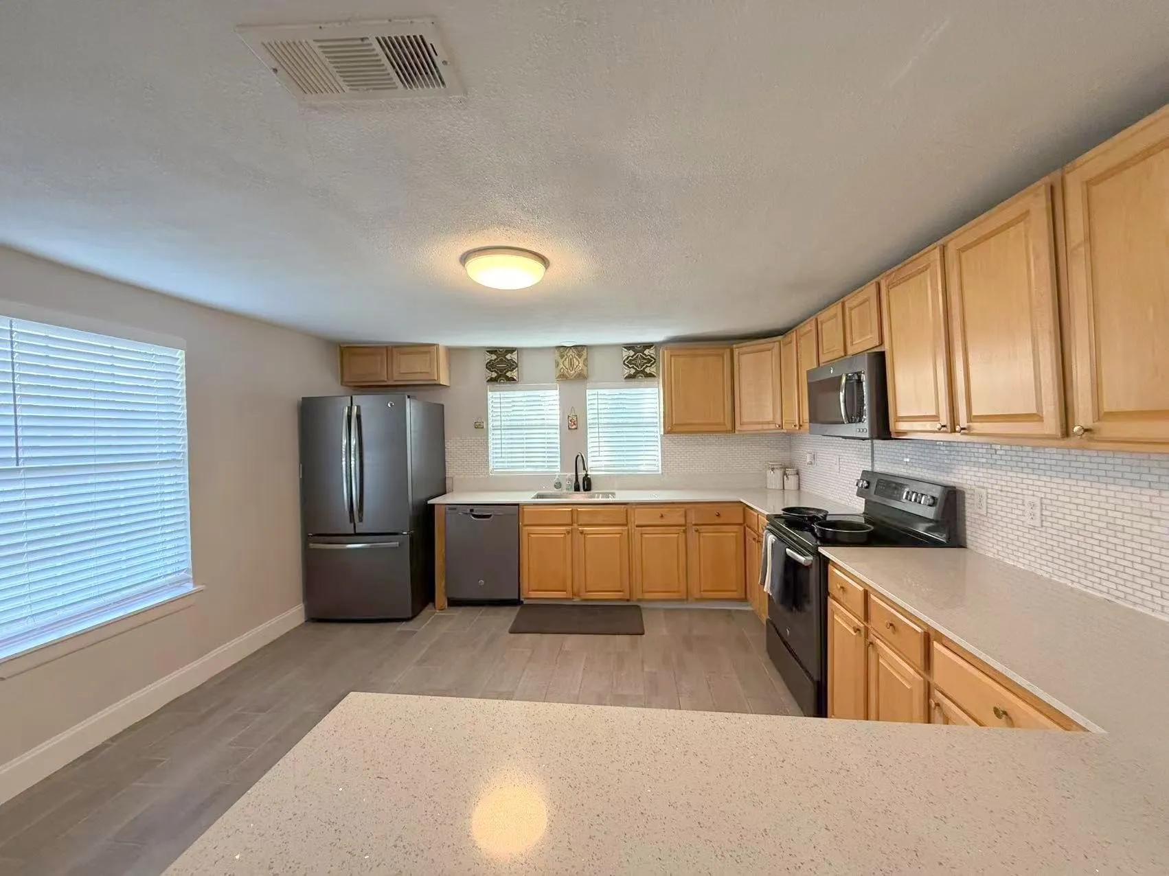 Kitchen featuring light wood cabinetry, white subway tile backsplash, and light-toned countertops