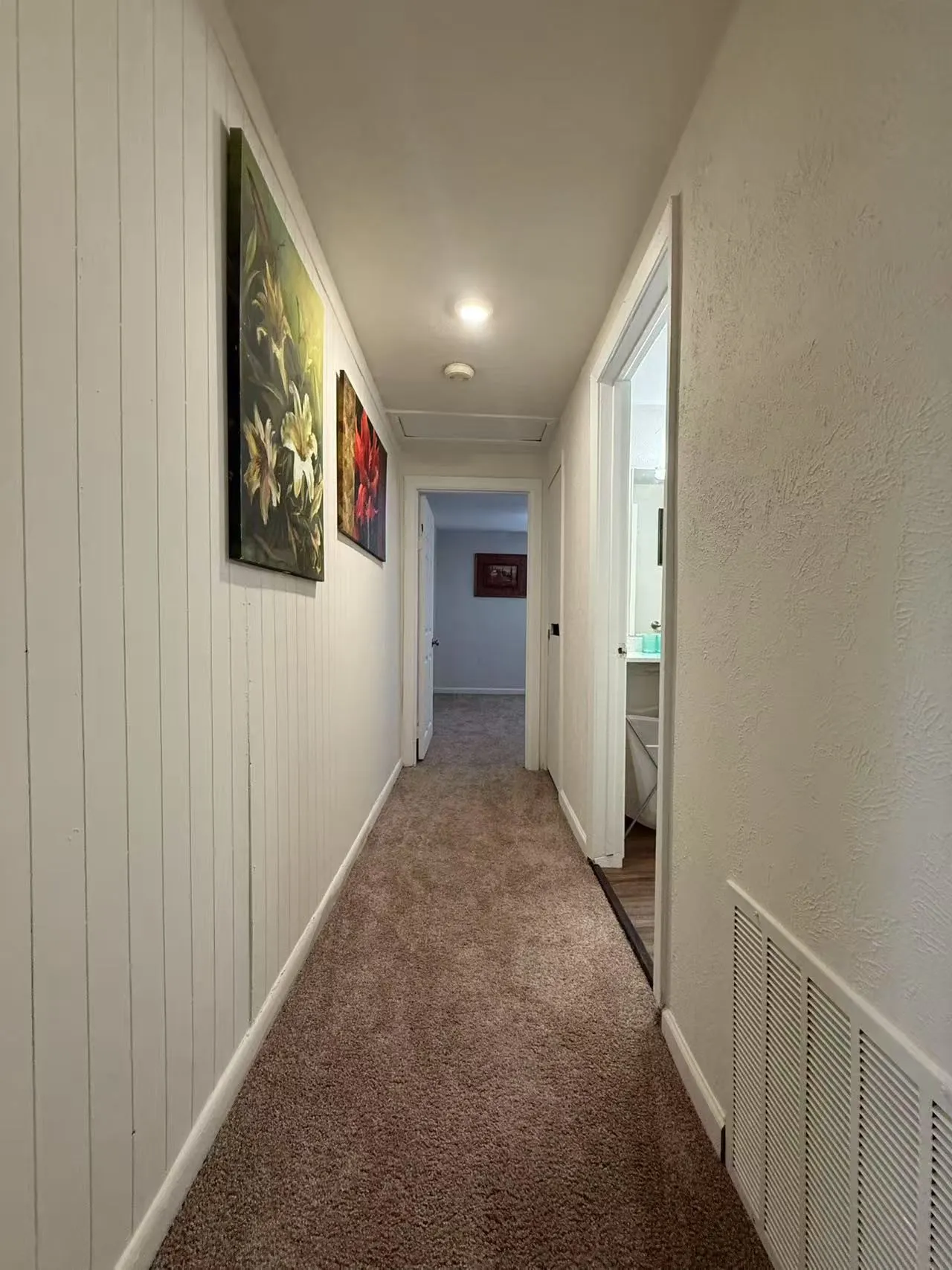 Carpeted hallway featuring vertical paneling, recessed lighting, and a white ceiling