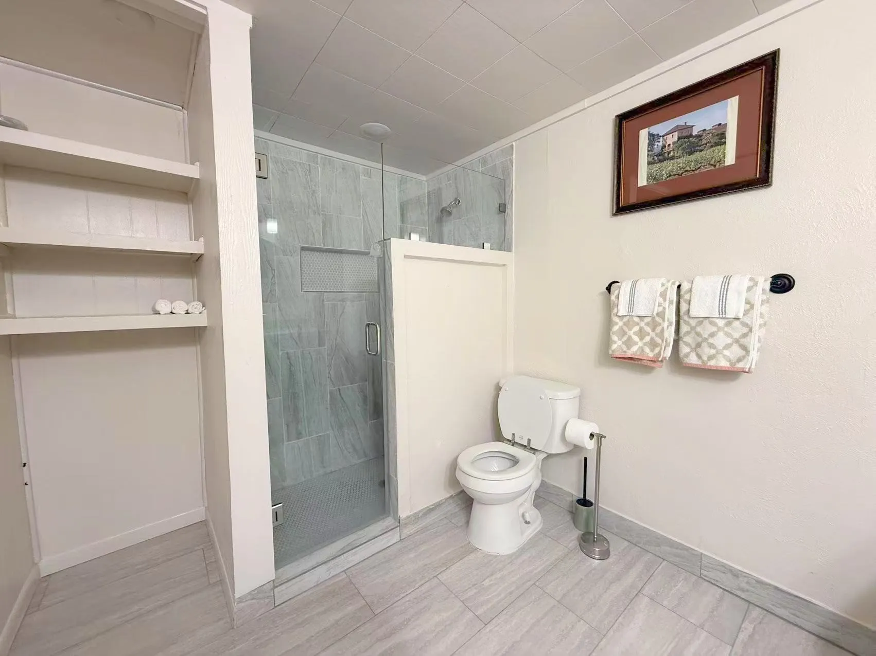 Full bathroom featuring a glass-enclosed shower with a built-in niche, light-toned wall tiling, and coordinating floor tiling